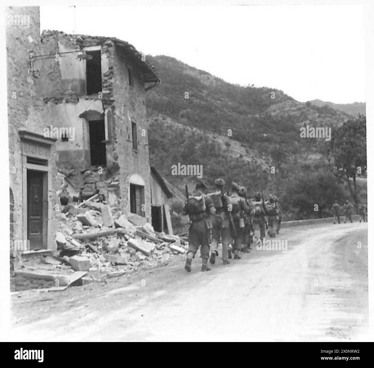 OTTAVO ESERCITO VARIE - Una sezione di fanteria britannica si sposta in avanti attraverso il villaggio di San Godenzo, passando l'ultima casa del villaggio malconcio. Negativo fotografico, British Army Foto Stock