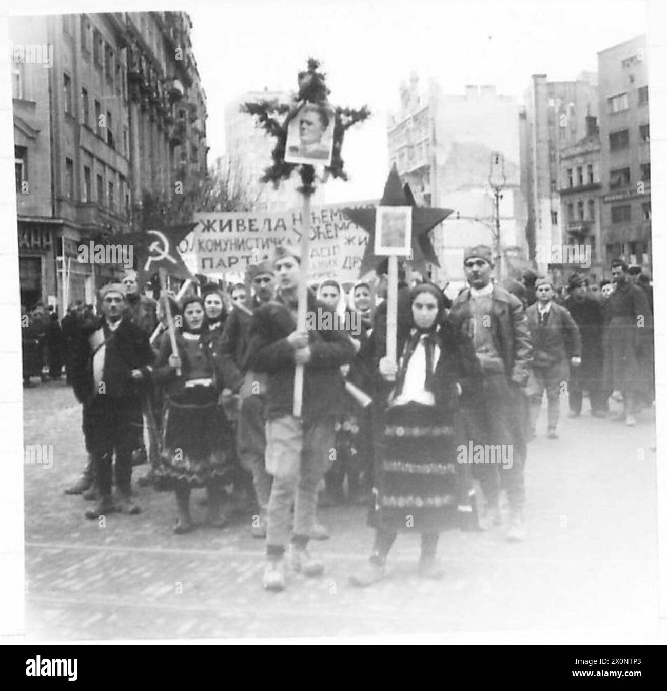 I partigiani e i manifestanti di Belgrado si fermano durante una marcia, portando con sé uno striscione con messaggi politici. Foto Stock