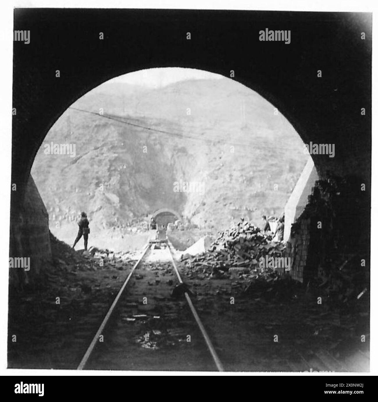 La vista dal portale nord del tunnel n. 16 mostra il ponte ferroviario a binario unico che collega il tunnel n. 17 durante la ricostruzione in Italia. Foto Stock