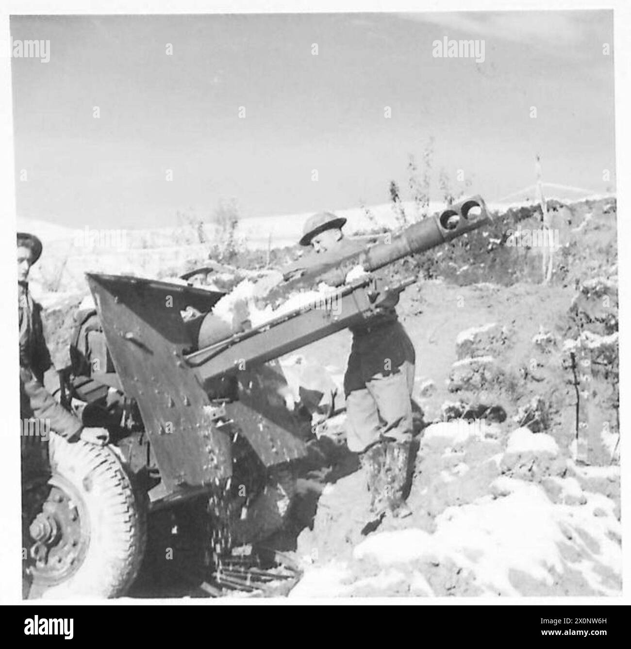 Un equipaggio di cannoni da 25 libbre pulisce la neve dalle loro attrezzature durante la prima nevicata in un settore della Quinta Armata. Negativo fotografico dell'esercito britannico. Foto Stock