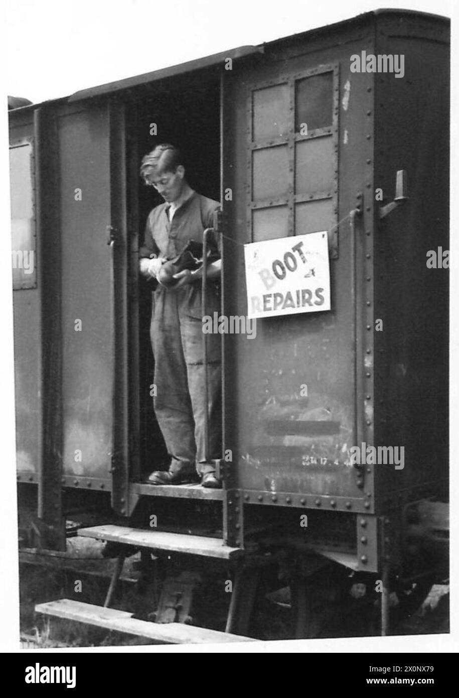 La polizia militare utilizza la stazione di Bayeux, mentre Sapper F.G. Pateman dell'esercito britannico gestisce un'officina di ciabattini all'interno di un furgone ferroviario tedesco. Foto Stock