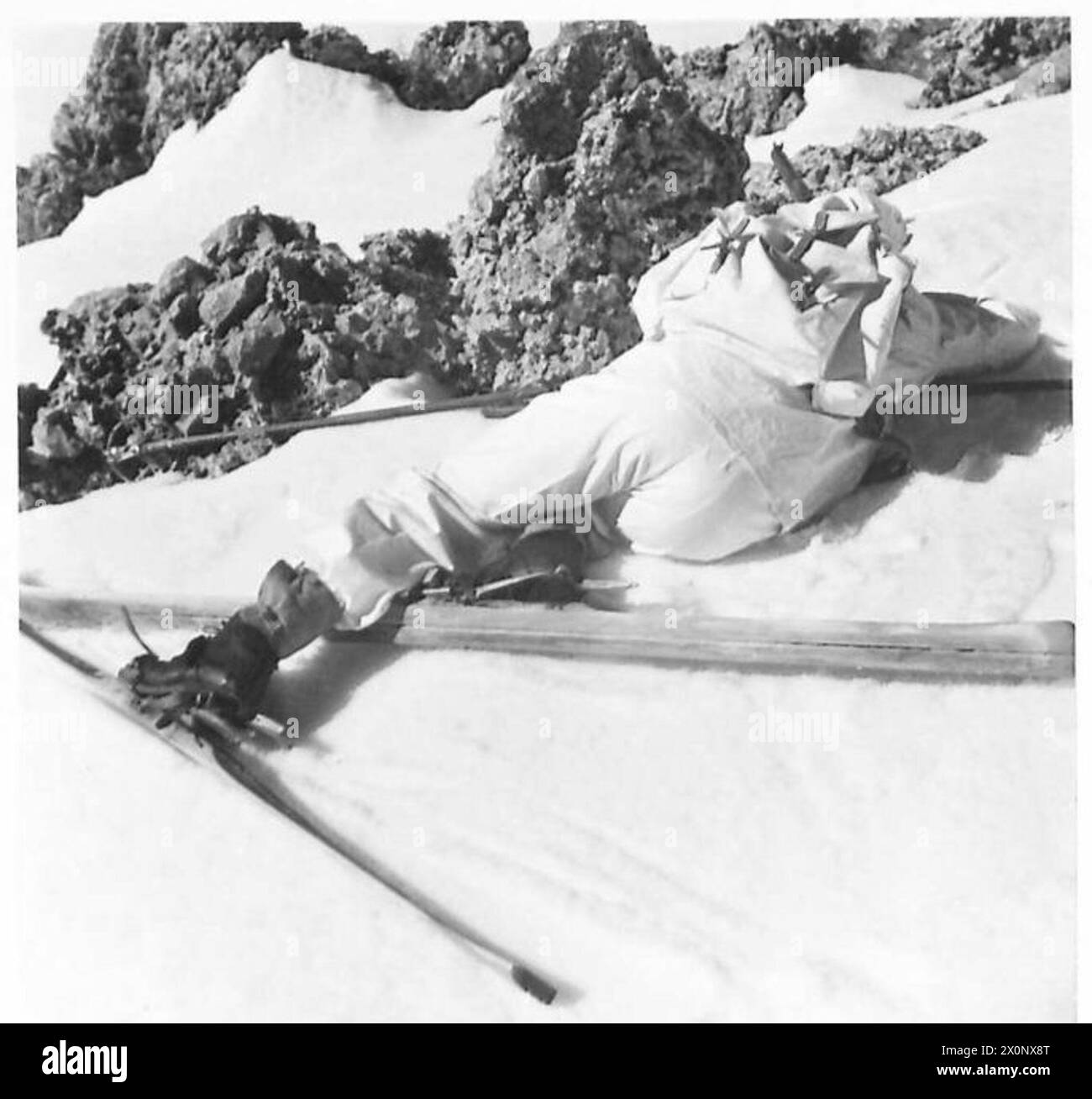 Fotografia delle truppe di sci che si coprono dietro le rocce durante l'addestramento su terreni innevati, sotto l'esercito britannico. Foto Stock
