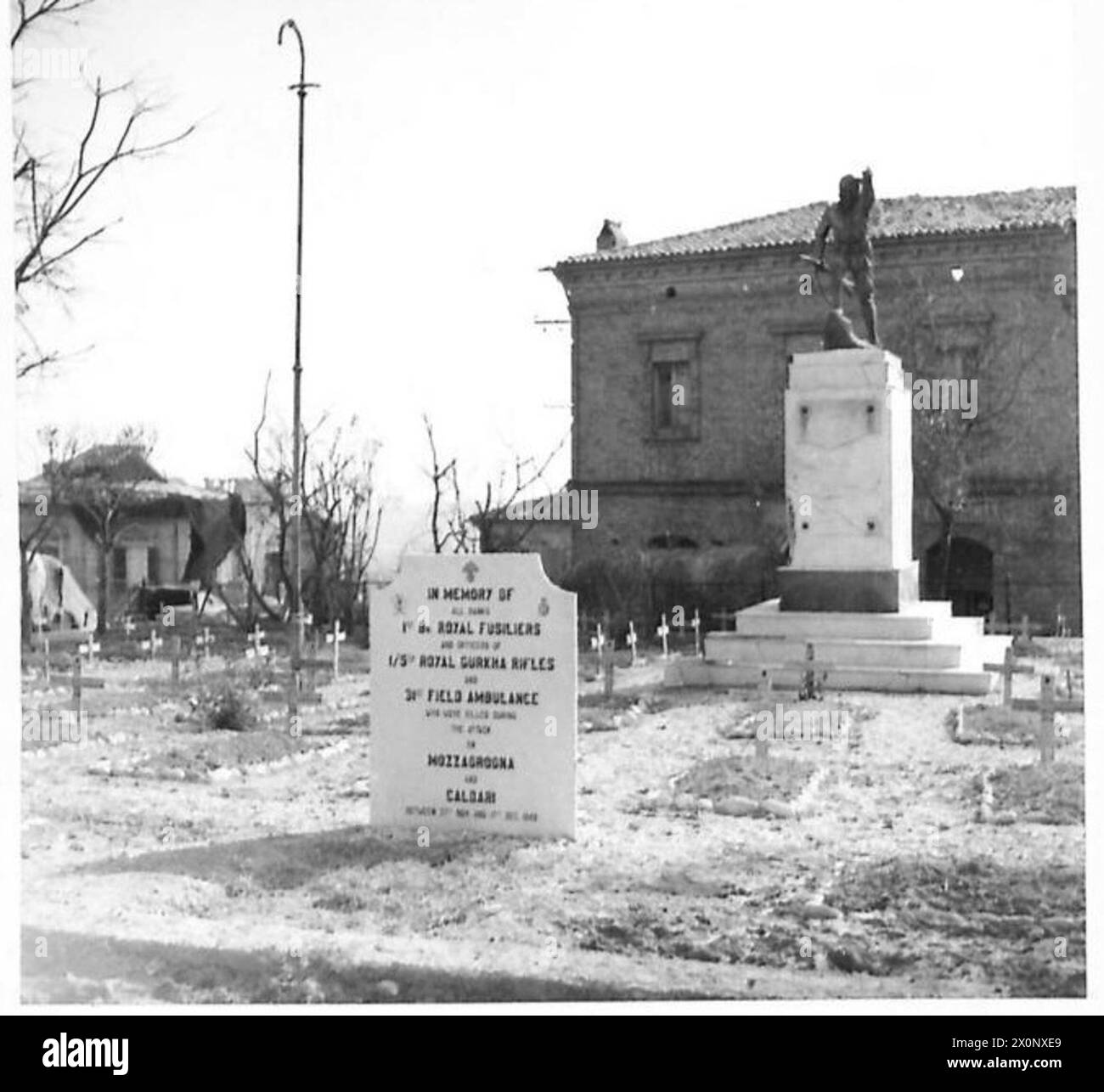 Una pietra commemorativa onora i fucilieri, i Gurkha e gli uomini delle ambulanze in una piazza del villaggio vicino al Memoriale di guerra italiano, circondata da tombe di soldati uccisi in battaglia. Foto Stock