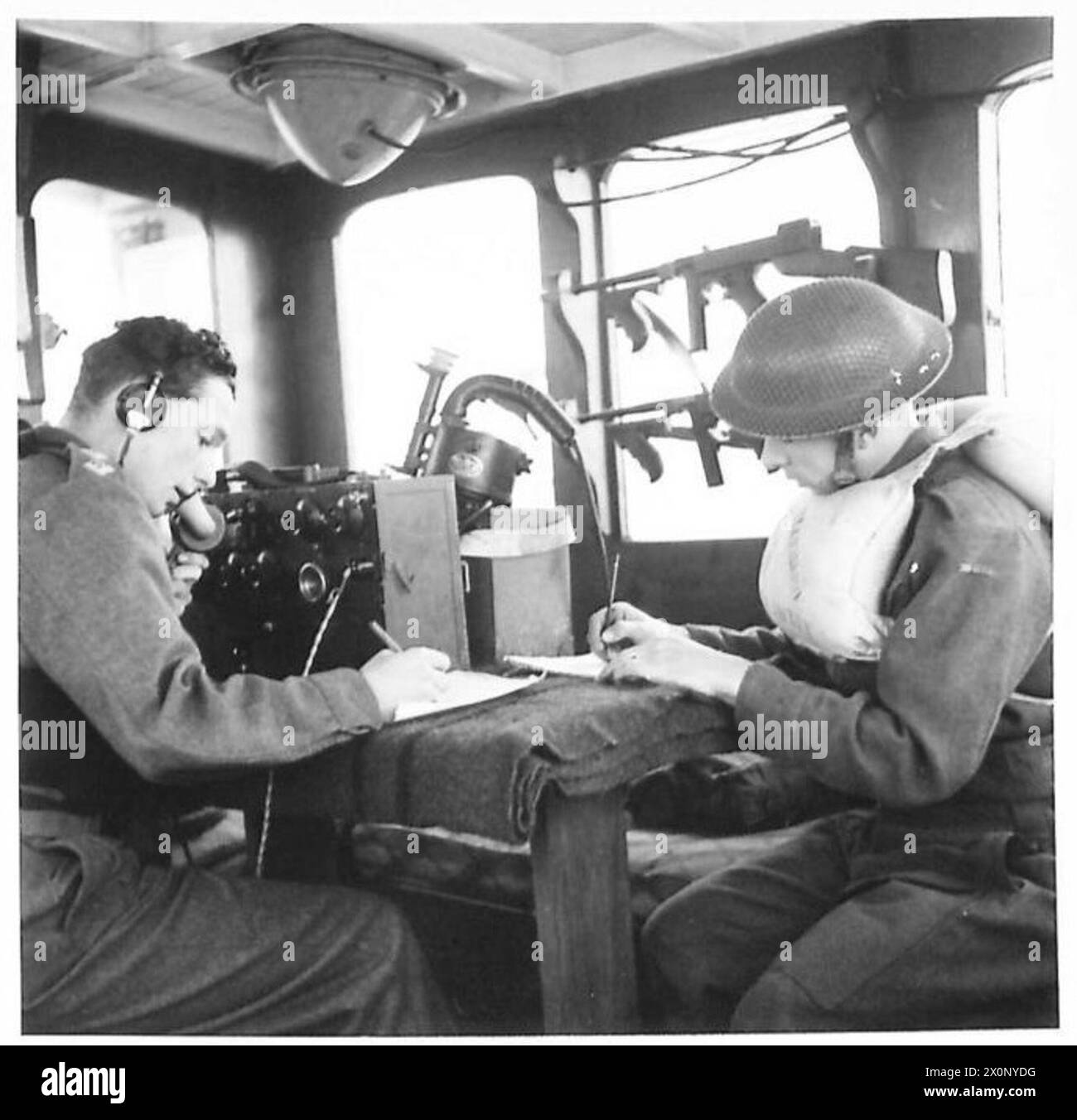 All'interno di una cabina wireless dell'esercito britannico, un ufficiale gestisce apparecchiature radio per comunicare e controllare il coordinamento tra le navi navali. Foto Stock