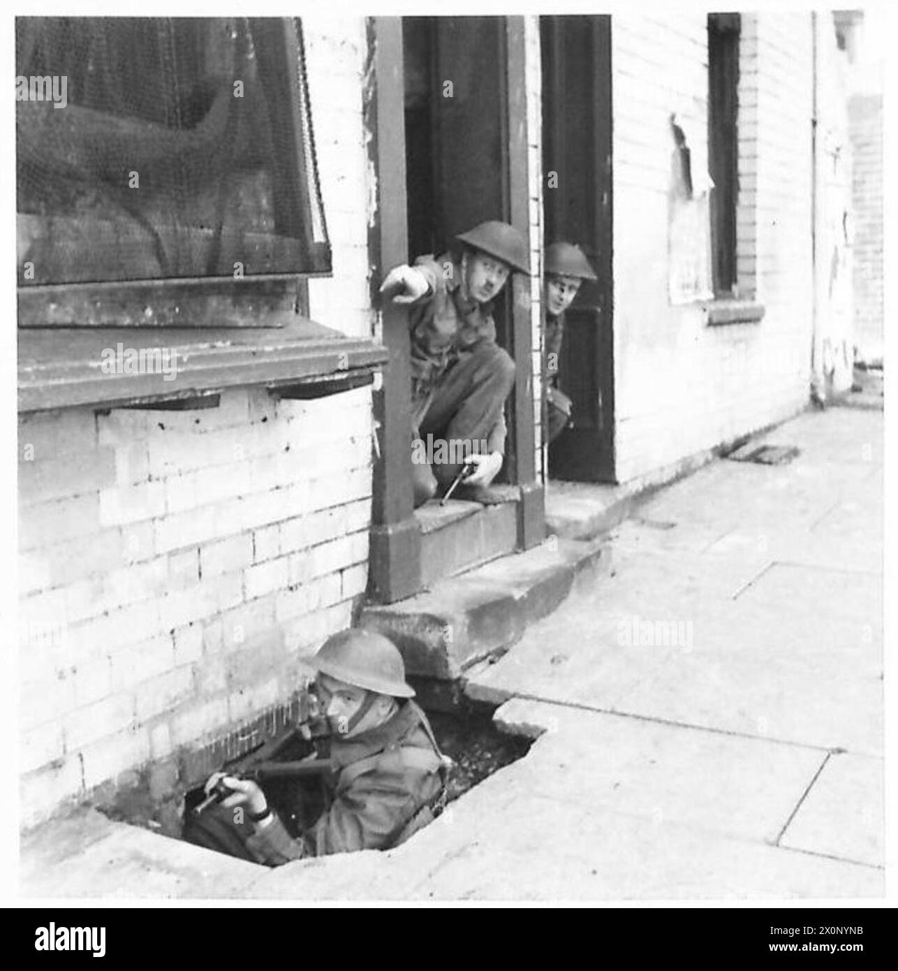 Un cannone Sten fornisce fuoco di copertura mentre il comandante del plotone impartisce istruzioni durante gli scontri di strada. Foto Stock
