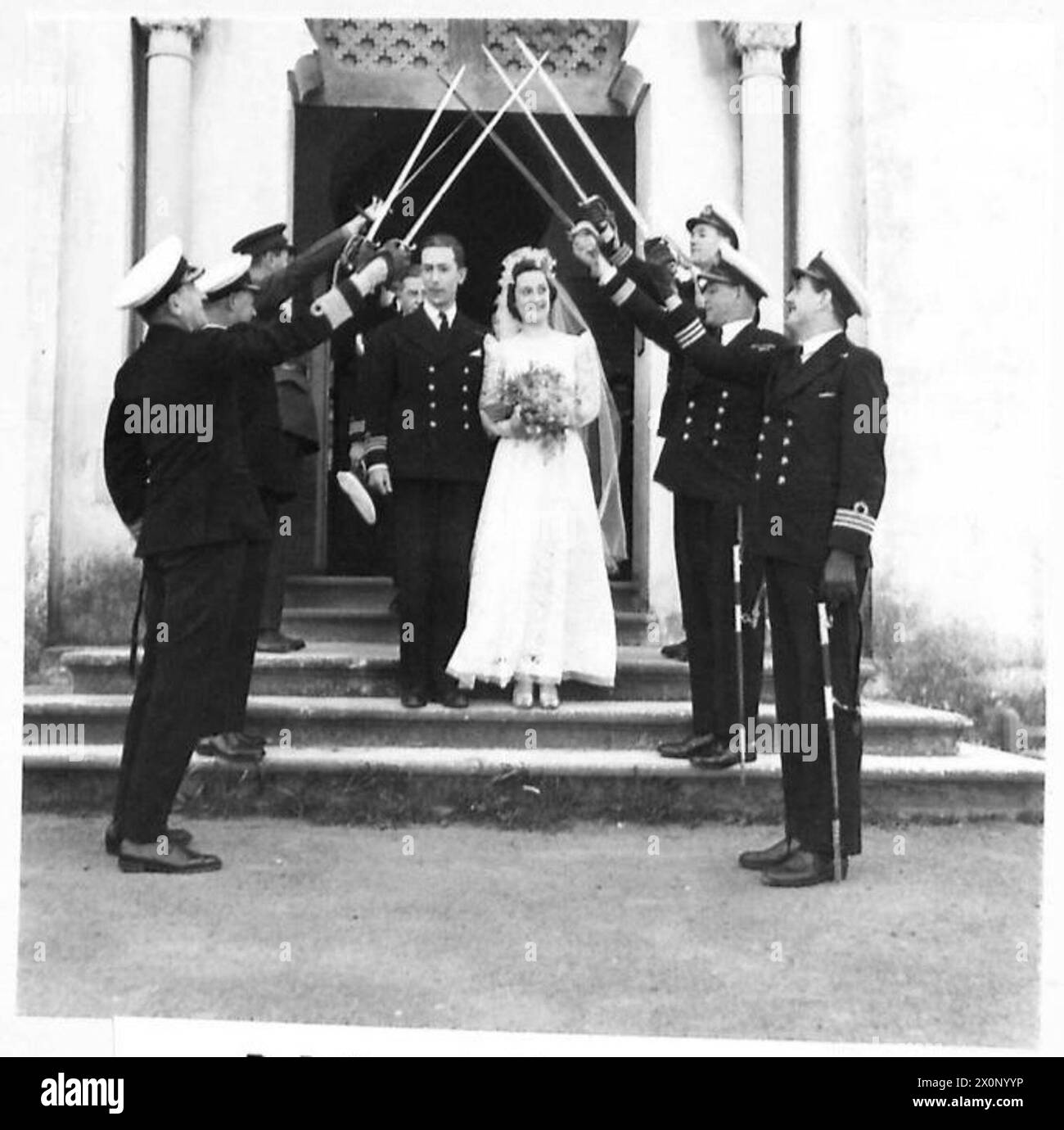 Un matrimonio navale in Nord Africa mostra la sposa e lo sposo che lasciano una chiesa sotto un arco di spada tenuto da ufficiali della Royal Navy. Foto Stock