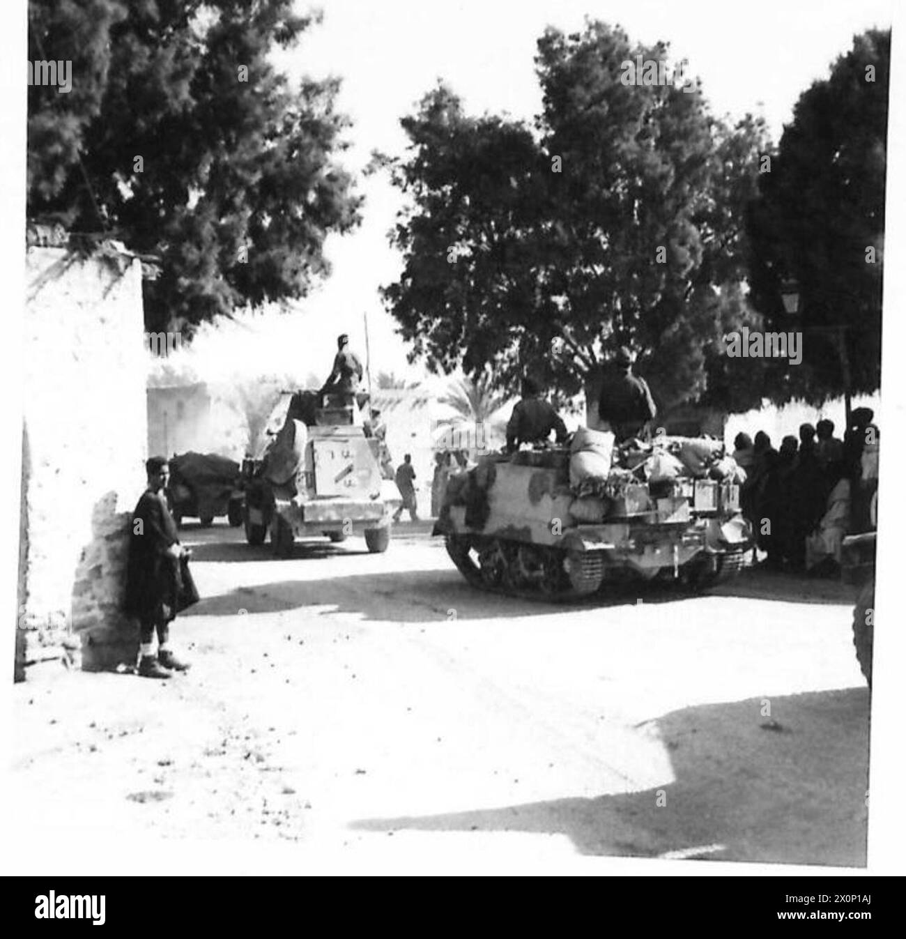 Il 29 marzo, dopo un bombardamento notturno di artiglieria, l'VIII Armata avanzò da El Hamma a Gabes, con veicoli corazzati che inseguivano il nemico mentre i civili locali osservavano. Foto Stock