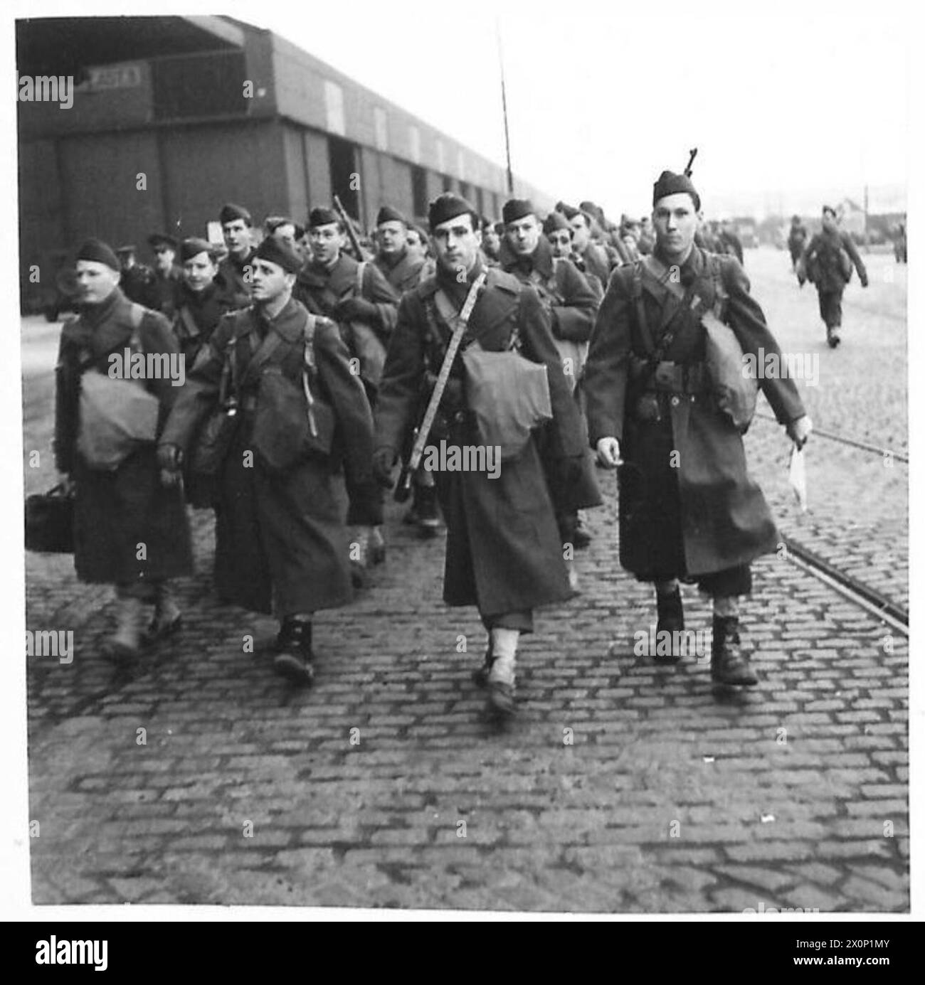 Negativo fotografico che mostra le truppe statunitensi che marciano lungo una banchina dopo lo sbarco, sembrando in forma e in forma. Foto Stock