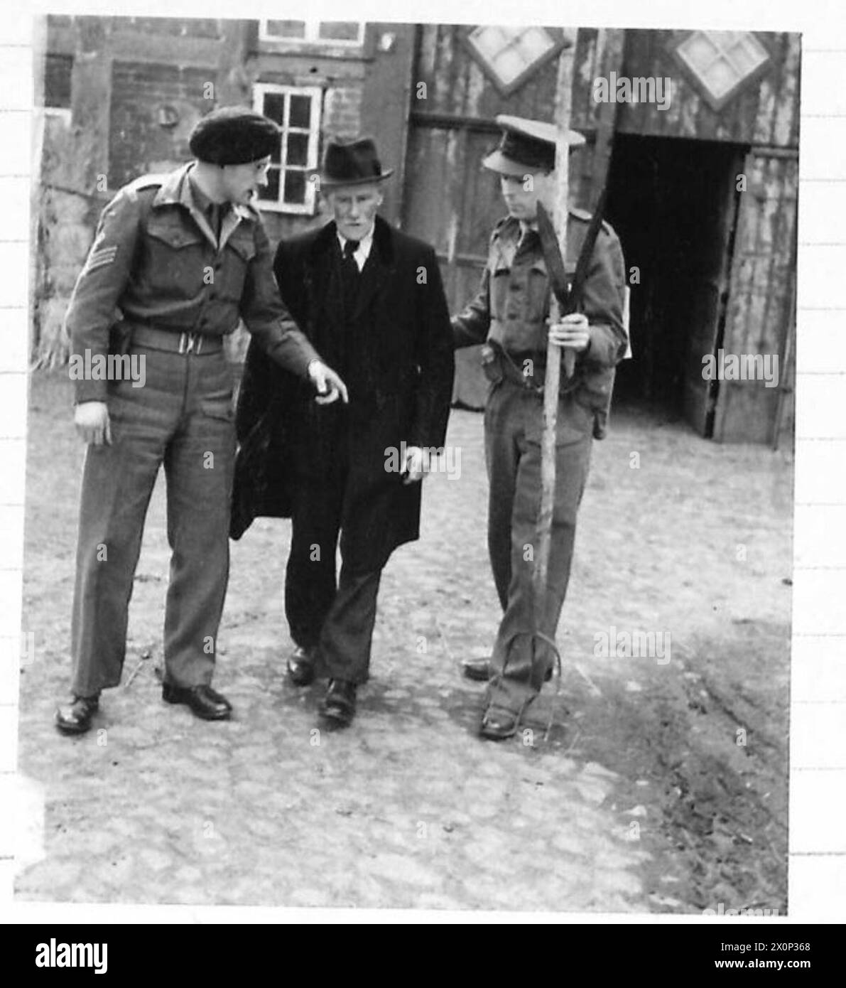 Fotografia che mostra Niermann, un sospetto tedesco, che lascia la sua fattoria sotto scorta del tenente Jack e del sergente maggiore Manning durante un'operazione di arresto. Foto Stock