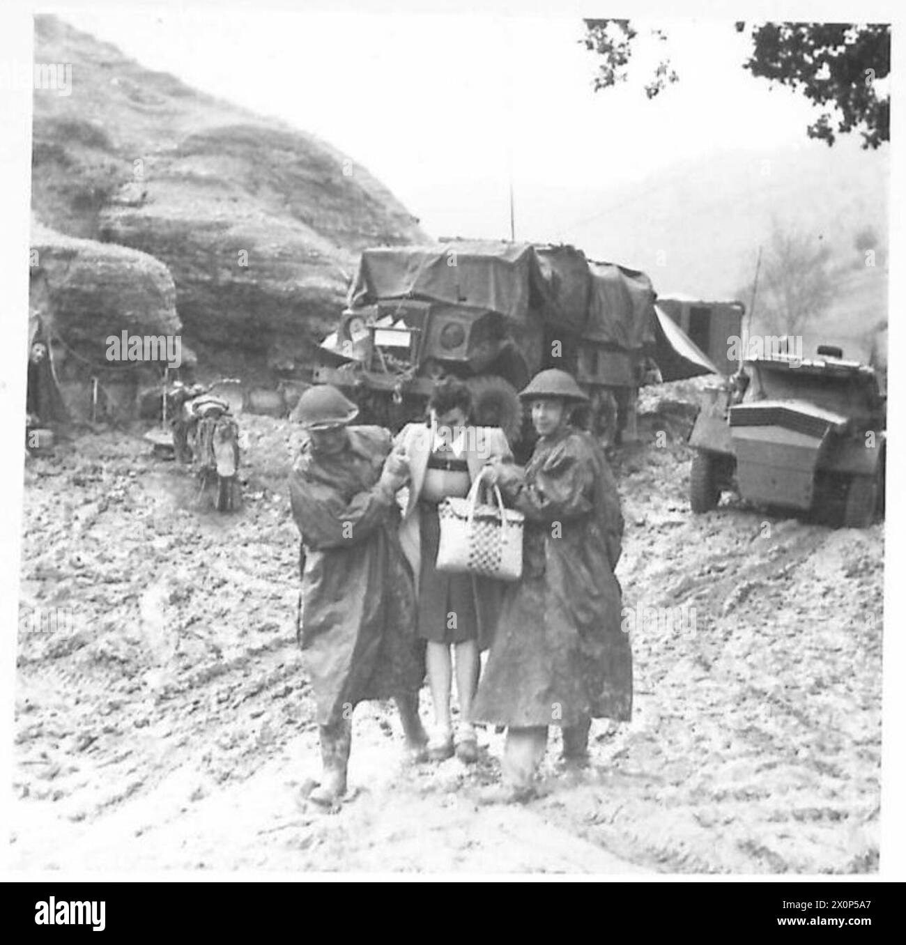 GNR. W. cucina e GNR. R.A. Clarke assiste una giovane donna italiana lungo una strada fangosa vicino a Valsalva in Nord Africa, Sicilia, Italia, Balcani e Austria. Negativo fotografico, British Army. Foto Stock