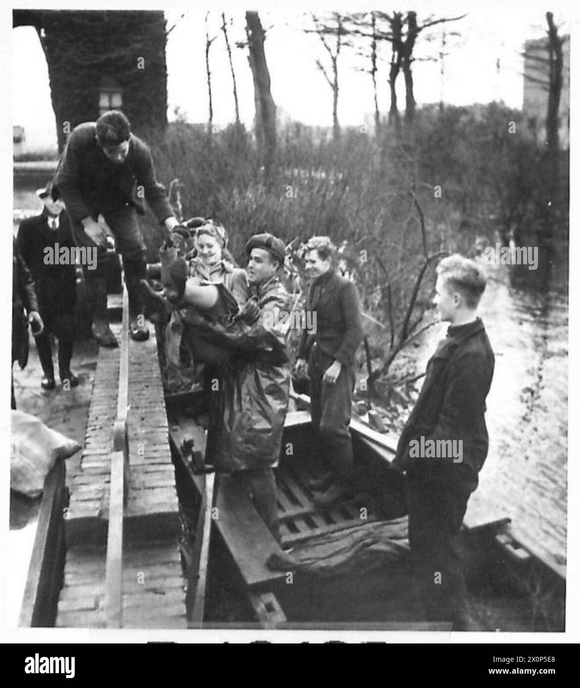 Negativo fotografico che mostra un soldato britannico che assiste una donna salvata a terra sull'isola allagata di Walcheren. Foto Stock