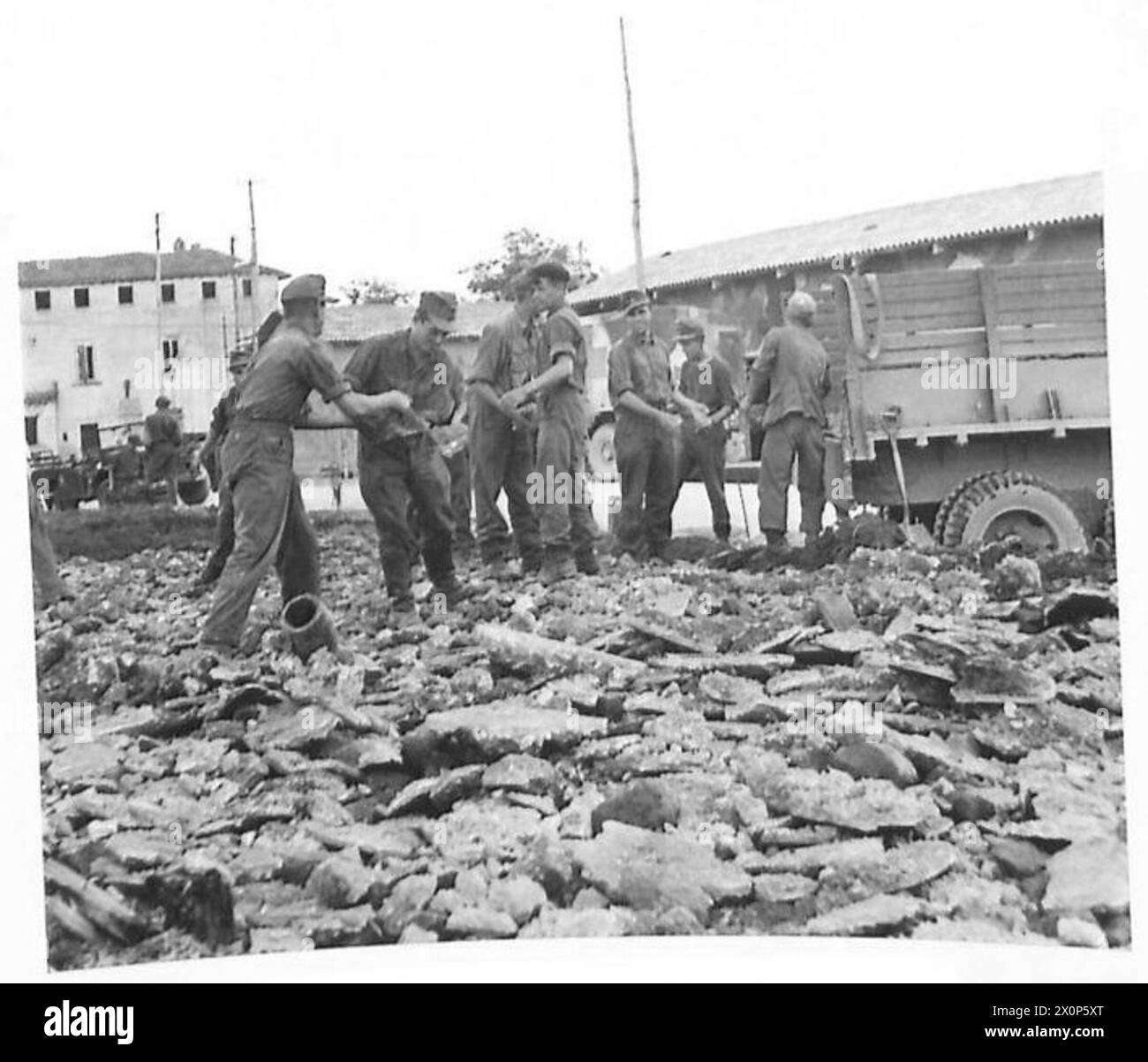 I prigionieri tedeschi lavorano in un campo, sgombrando e riparando recinzioni sotto supervisione sul fronte della Quinta Armata in Italia. Foto Stock