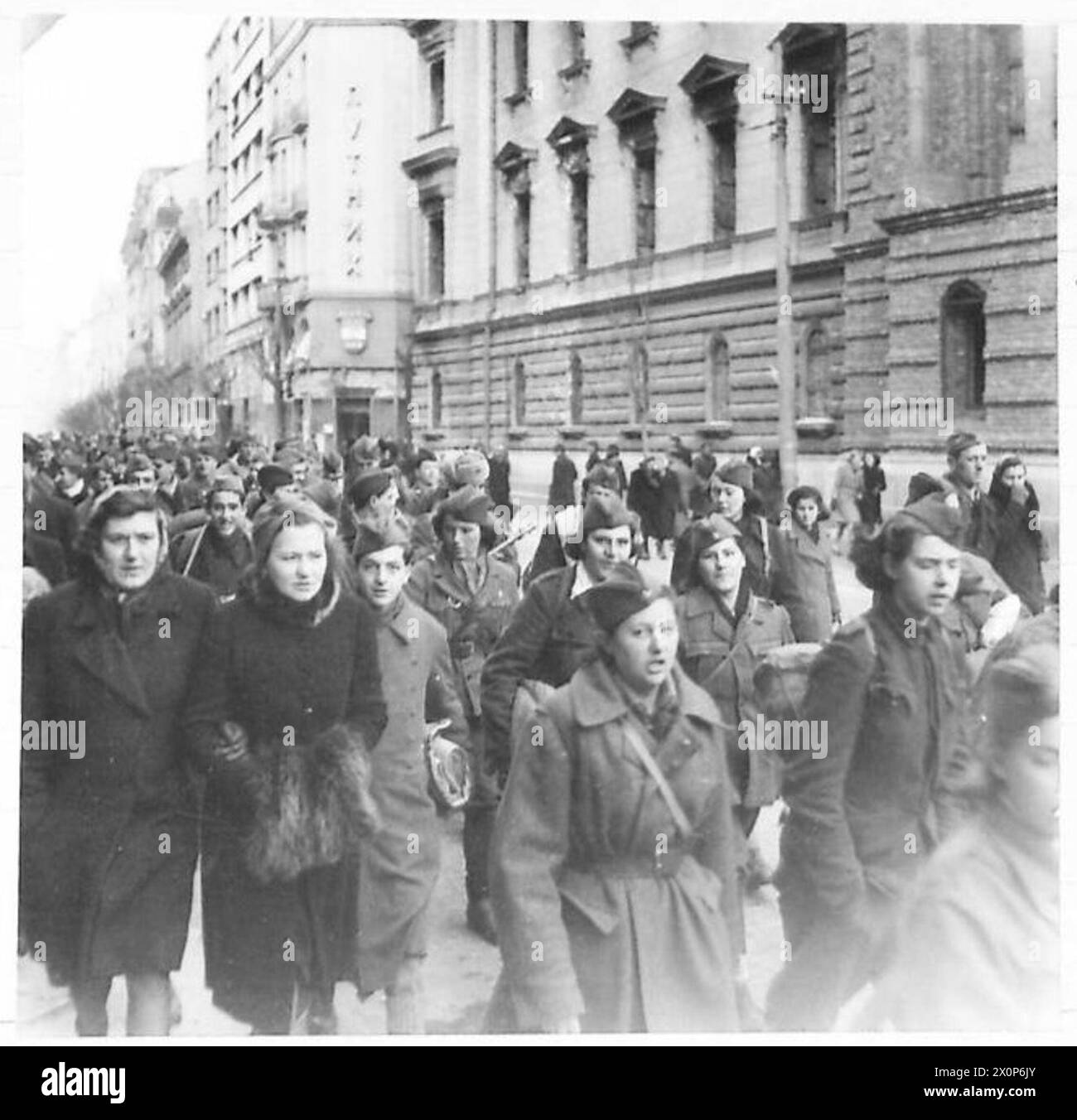 I partigiani jugoslavi marciano attraverso Belgrado con donne che partecipano a fianco degli uomini, dimostrando la composizione mista di genere delle forze di resistenza durante la seconda guerra mondiale Foto Stock
