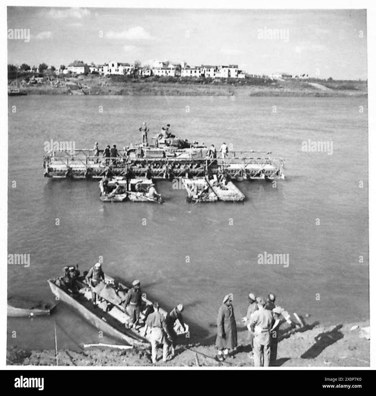 Un carro armato Churchill dell'Ottava Armata attraversa il fiume po via traghetto, mentre un soldato tedesco ferito viene evacuato da un mezzo d'assalto. Foto Stock
