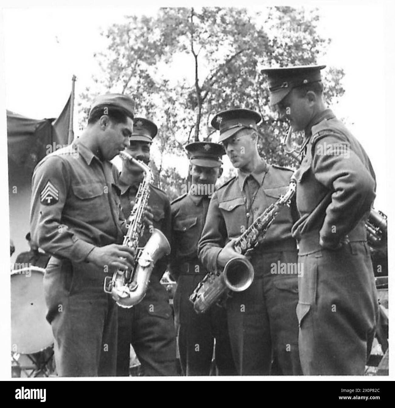 Il sergente T. Duva (americano) dimostra la tecnica del sassofono ai musicisti S. Knight, L. Ward, A. Upchurch e W. Luscombe della London Guards Band durante un tour. La fotografia documenta l'addestramento musicale e le attività culturali all'interno dell'esercito britannico. Foto Stock