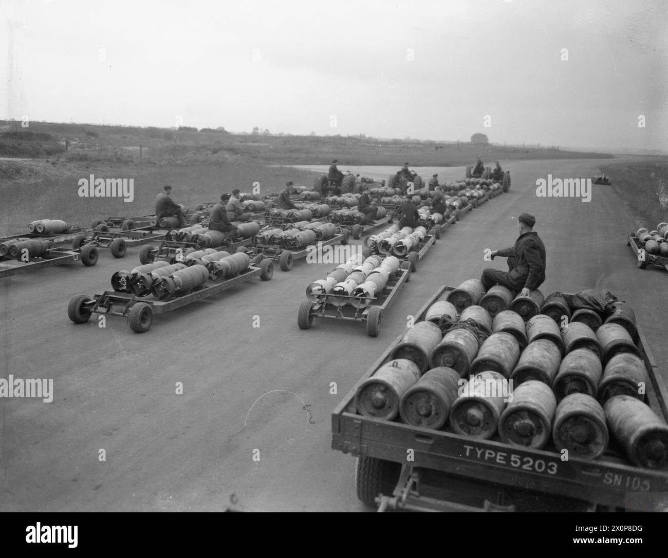 I carrelli caricati con bombe GP e MC da 500 lb e i loro corazzati furono trainati da trattori dal Bomb Store di Snaith, nello Yorkshire, alle dispersioni di aerei per la Handley Page Halifaxes del No. 51 Squadron RAF a supporto delle operazioni alleate in Normandia. Negativo fotografico. Foto Stock