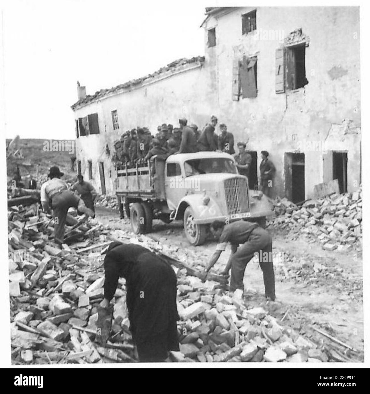 I prigionieri tedeschi vengono guidati con il loro camion davanti agli italiani alla ricerca di rovine durante l'attraversamento dell'Adige da parte dell'ottava armata. Foto Stock