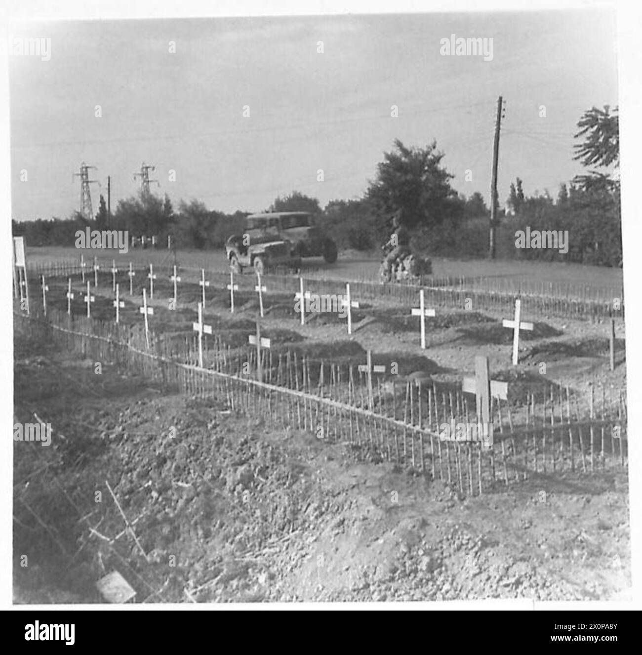 Un cimitero militare canadese si trova accanto a una strada principale durante le operazioni che coinvolgono l'Ottava Armata. Foto Stock