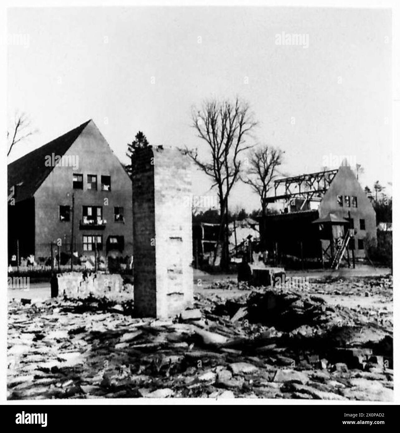 Negativo fotografico che mostra il campo di prigionia Oflag 79 a Brunswick, in Germania, dall'esterno con garage in rovina in primo piano distrutti dalla RAF, illustrando le condizioni dei prigionieri di guerra durante la guerra. Foto Stock