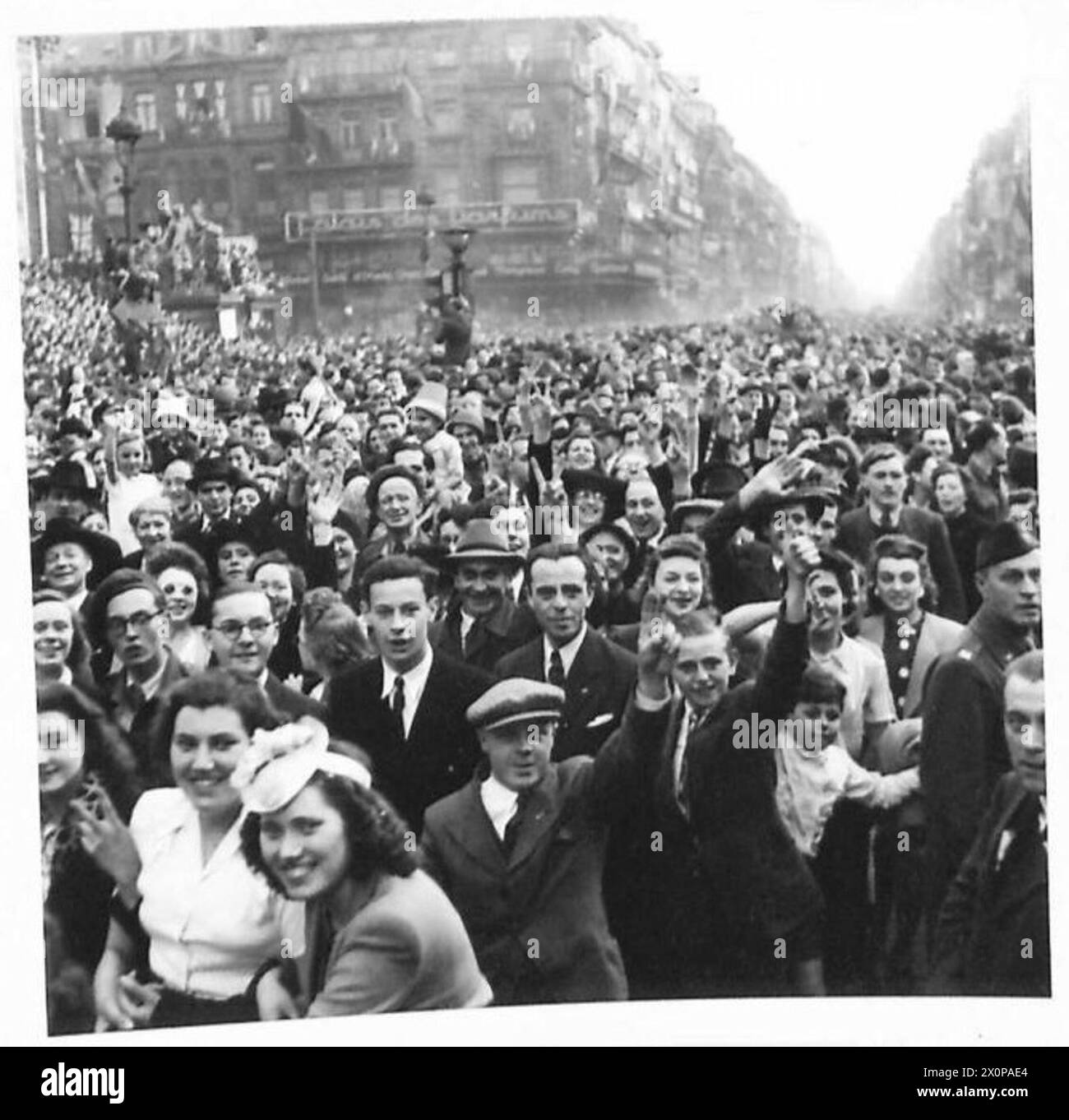 La folla si riunisce nel centro di Bruxelles per celebrare la giornata della Vittoria in Europa (V.E.), che segna la fine della seconda guerra mondiale in Europa. La fotografia cattura scene giubilanti mentre la gente del posto e il personale dell'esercito britannico del 21st Army Group si uniscono ai festeggiamenti, riflettendo il diffuso sollievo e la celebrazione in tutta l'Europa liberata. Foto Stock