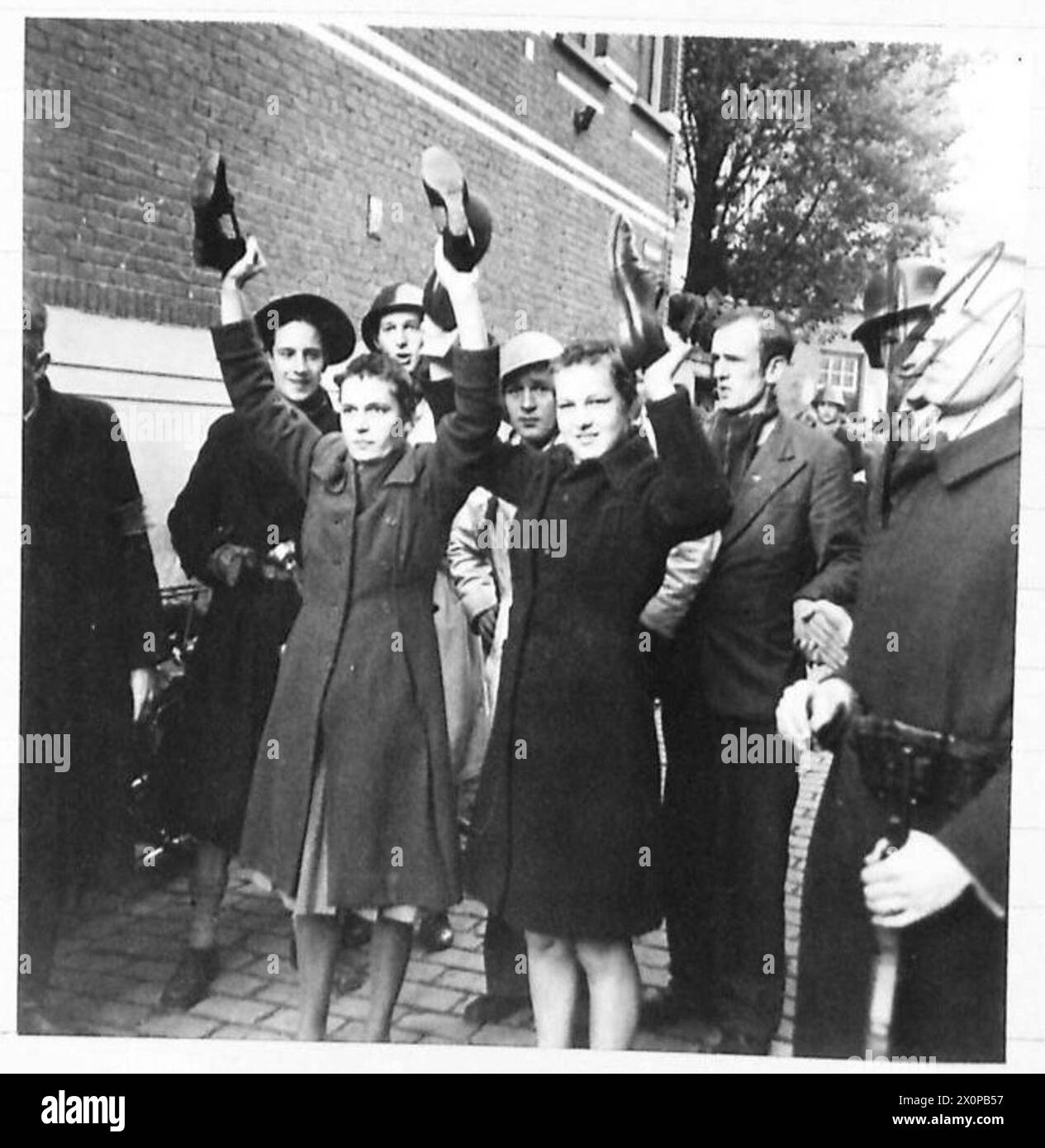 Una donna identificata come collaboratrice è costretta a camminare a piedi nudi per le strade, tenendo le scarpe sopra la testa, come documentato dal British Army, 21st Army Group. Foto Stock