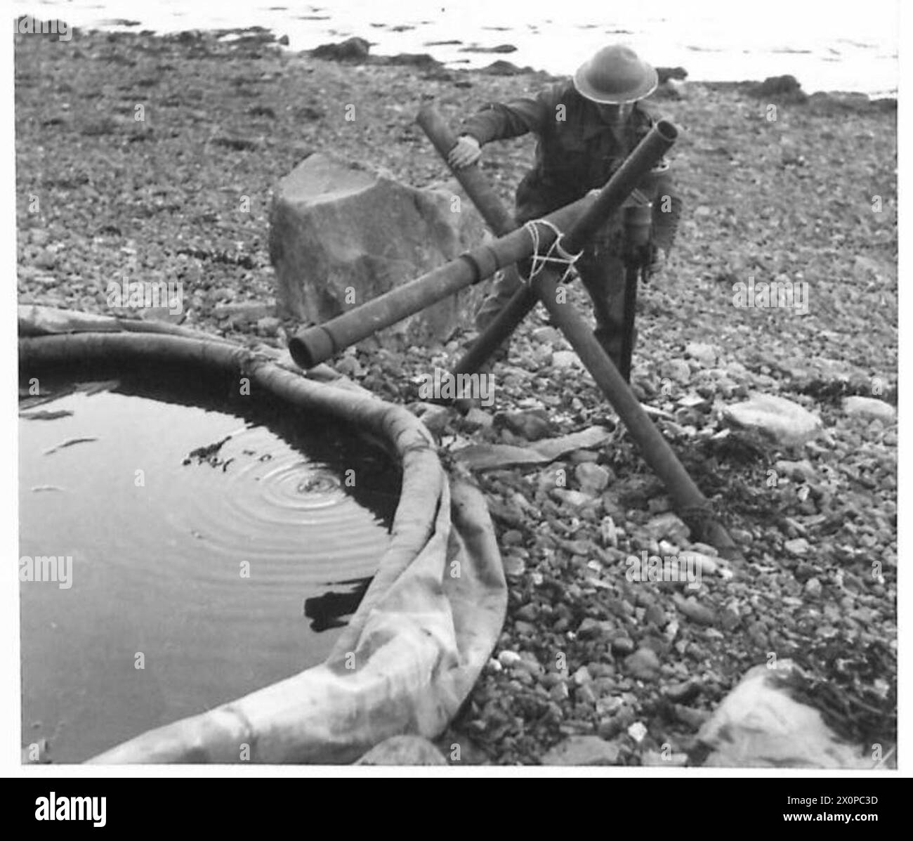 Il pozzetto del tubo Norton viene mostrato mentre pompano in cima a un litorale, illustrando le attrezzature di approvvigionamento idrico utilizzate dall'esercito britannico. Foto Stock