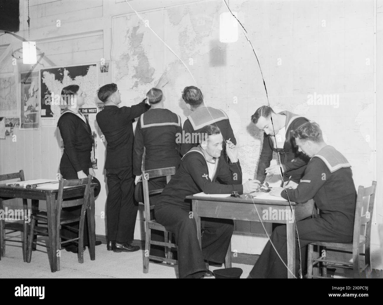 Ad Harwich il 27 luglio 1944, una stalla convertita "Sailor's Rest" serve come sala di riposo e informazione dove un maestro di scuola navale esamina una mappa dell'Europa con valutazioni. Foto Stock