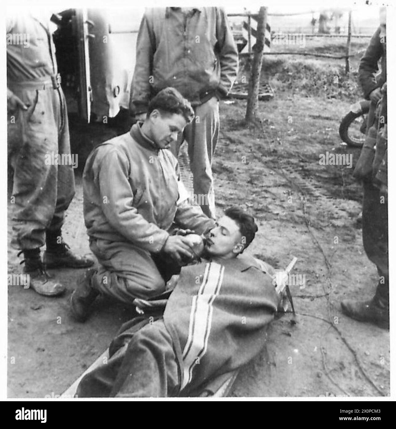 Stephen Zabur di Arkon, Ohio, che serve con un'American Field Ambulance Unit, fornisce acqua a un soldato tedesco ferito durante le operazioni in Nord Africa, Sicilia, Italia, Balcani e Austria tra il 1942 e il 1946. Foto Stock