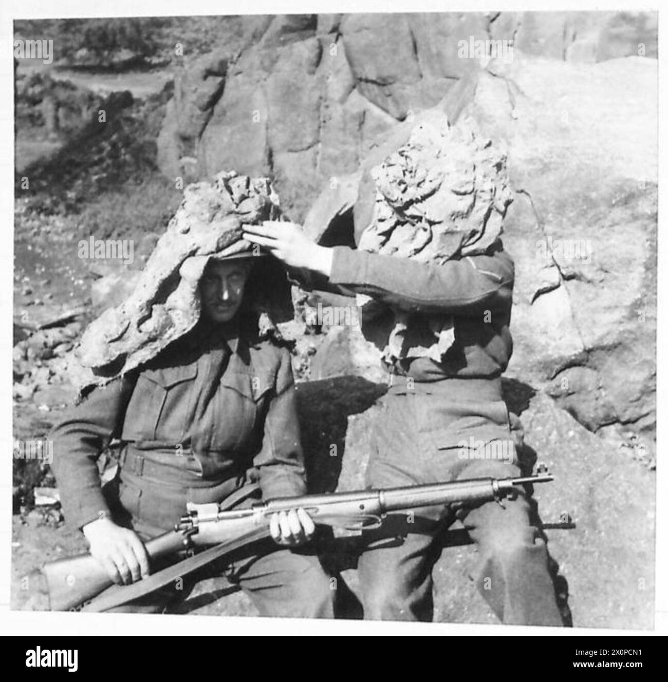 Soldati che regolano gli abiti da testa di roccia durante la preparazione sul campo. Negativo fotografico, British Army. Foto Stock