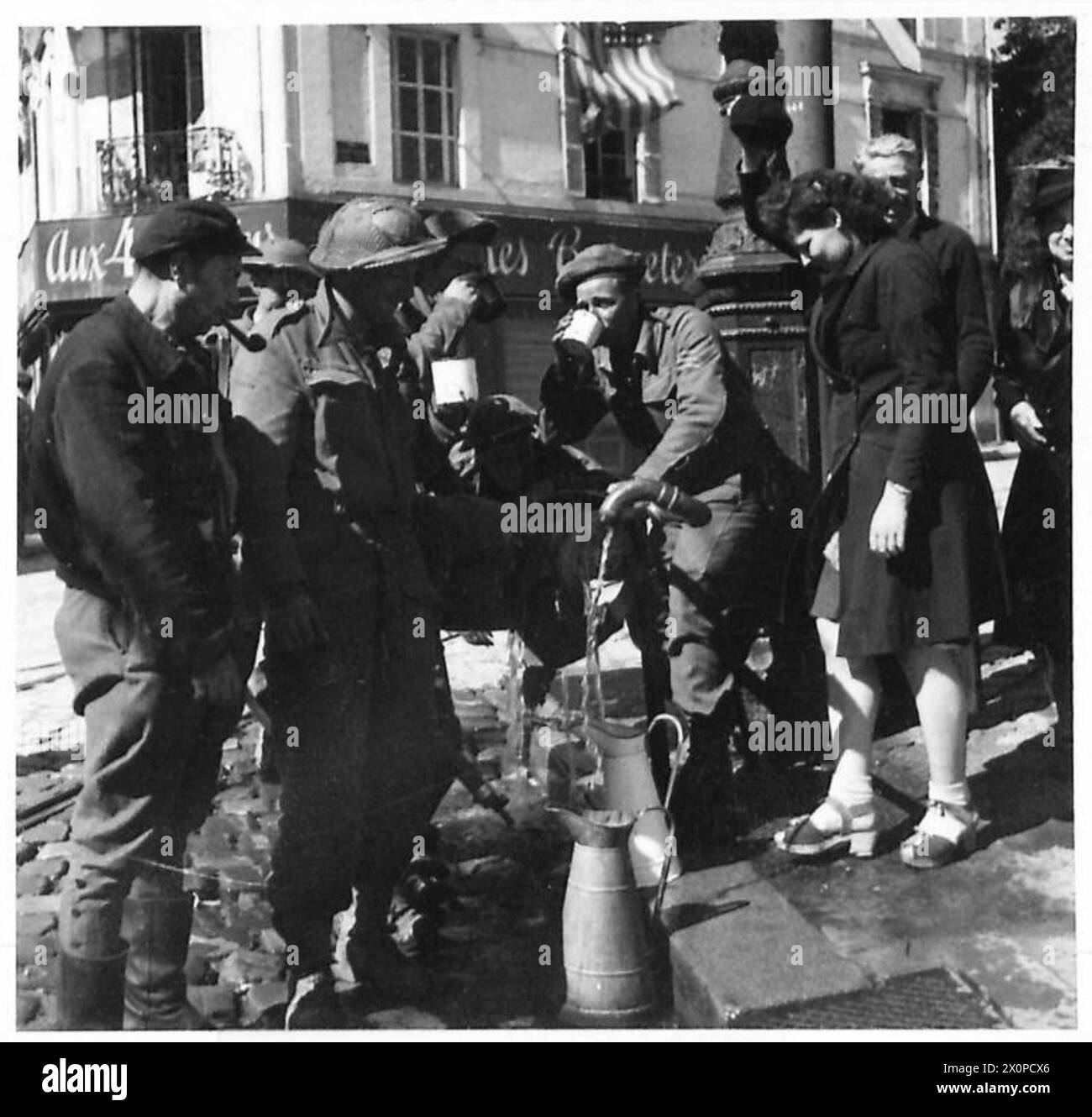 Le truppe britanniche e i civili locali a le Havre condividono un momento di relax con un drink in un ambiente di strada. La scena riflette la vita quotidiana e l'interazione civile durante l'occupazione in tempo di guerra. Foto Stock