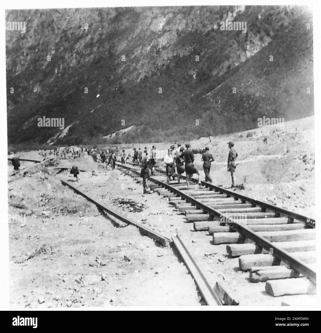 Un team di riparazione tedesco lavora su una linea ferroviaria in Italia, con il terreno circostante danneggiato da crateri bomba. Foto Stock