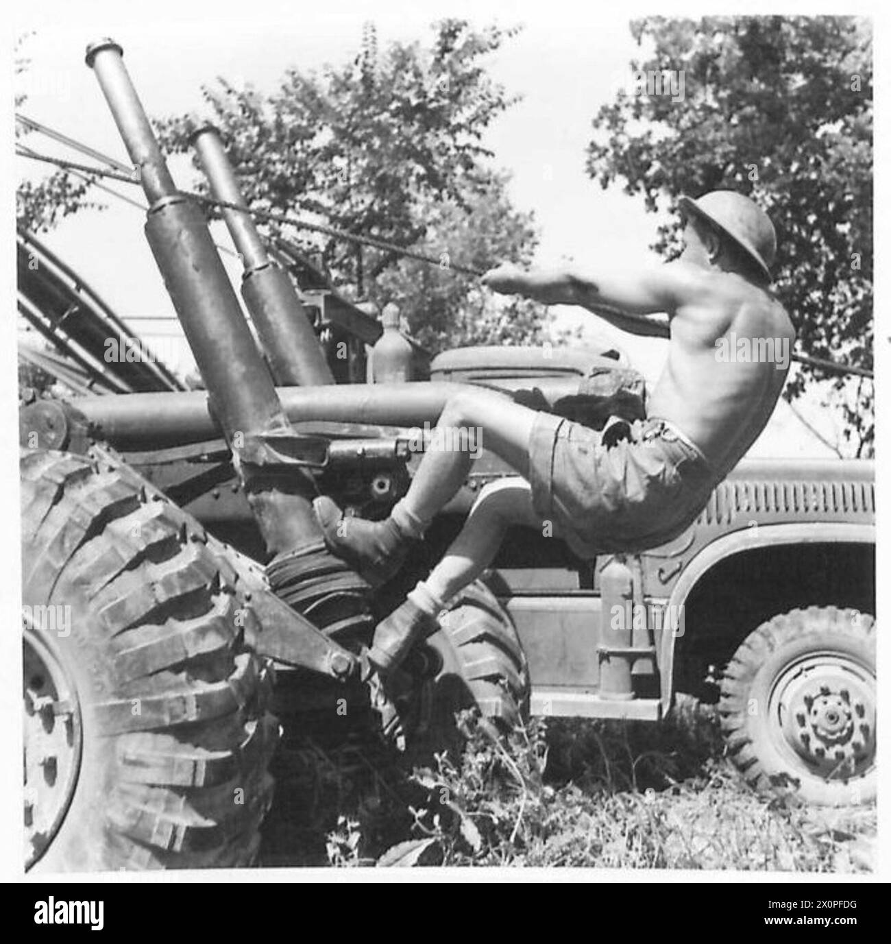 Il personale addetto alle armi solleva e posiziona una canna media pesante durante le operazioni di manutenzione sul campo. Foto Stock