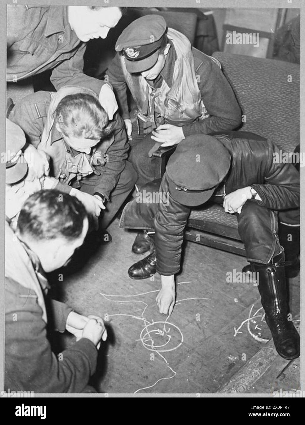 I piloti di Typhoon in una stazione di caccia britannica osservano il leader dello Squadrone Beamont DFC dimostrare tattiche di combattimento aereo usando il gesso sul pavimento di una capanna dispersa. Foto Stock