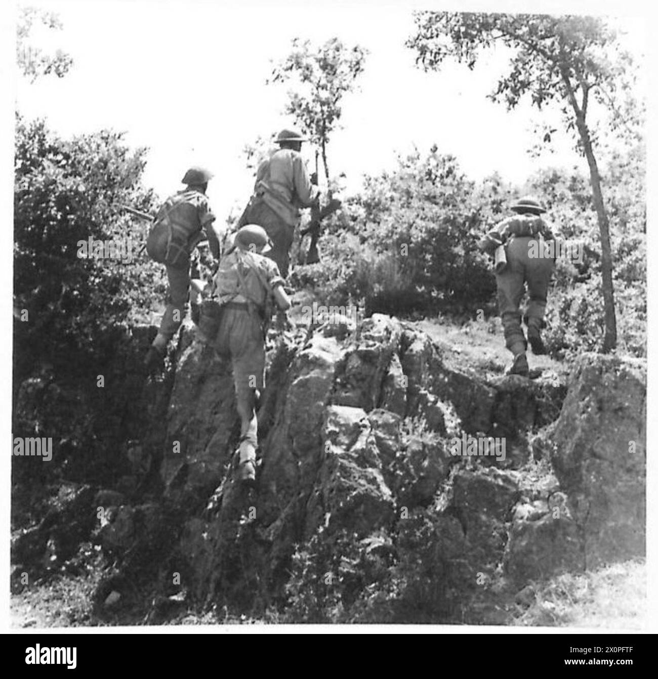 La fotografia mostra una pattuglia dell'Ottava Armata che si muove attraverso una montagna boscosa e rocciosa, che si schianta da copertura a copertura sotto osservazione da un terreno più alto durante il combattimento con le forze tedesche. Foto Stock