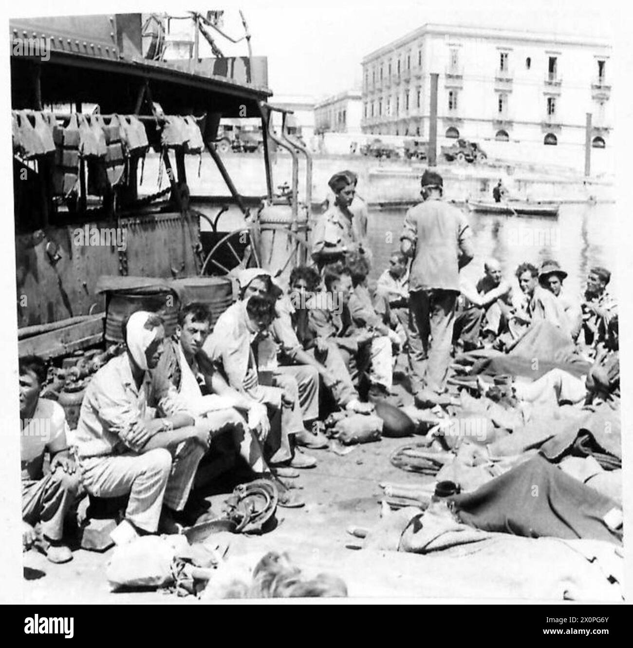 Le truppe alleate ferite a Siracusa attendono di salire a bordo di mezzi da sbarco per il trasporto verso una nave ospedale. Negativo fotografico, British Army. Foto Stock