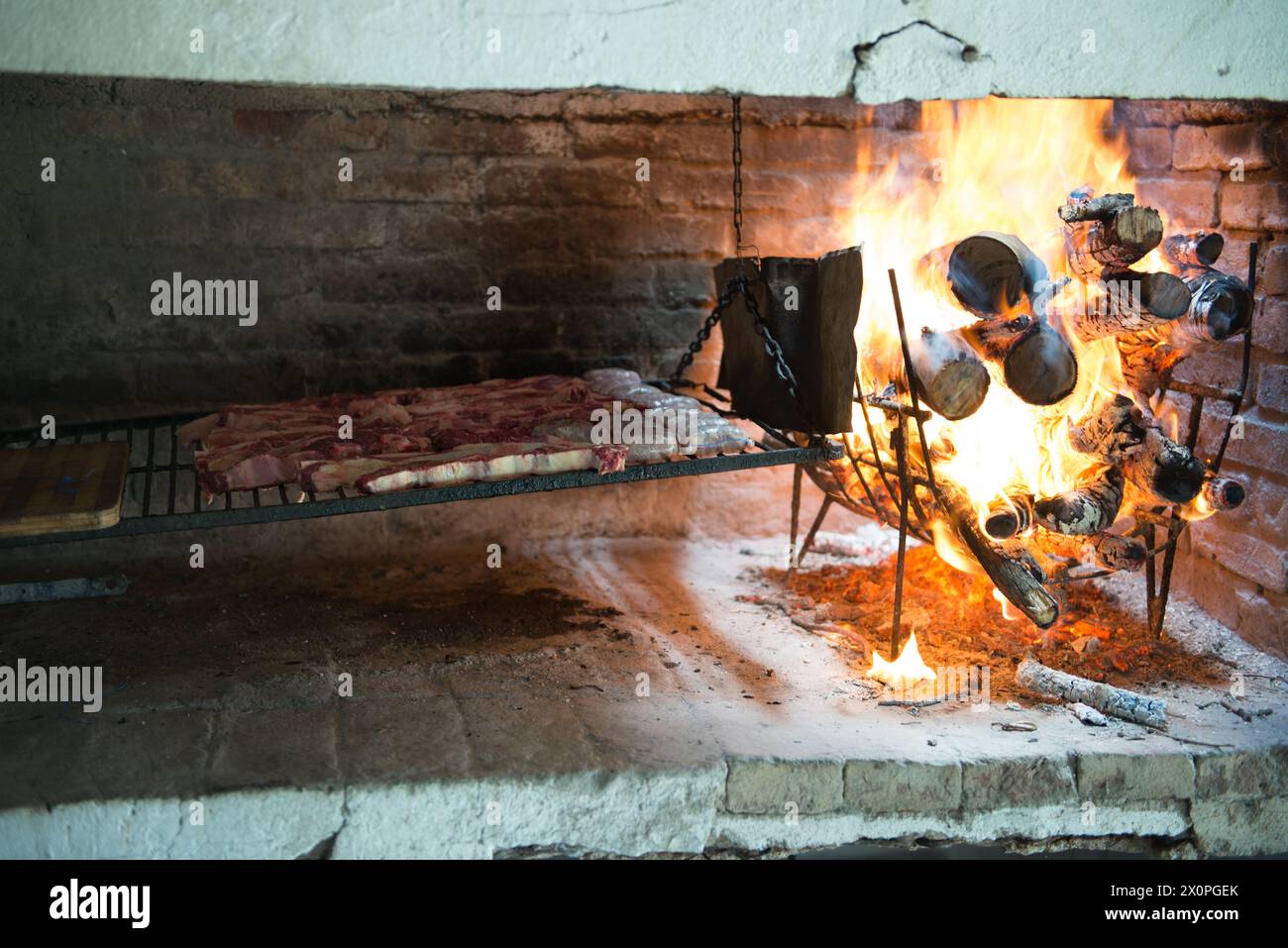 Un tradizionale focolare aperto e' abbellito da legna da ardere, fornendo calore alle pentole di ghisa sospese sopra le fiamme. L'ambiente rustico sugge Foto Stock