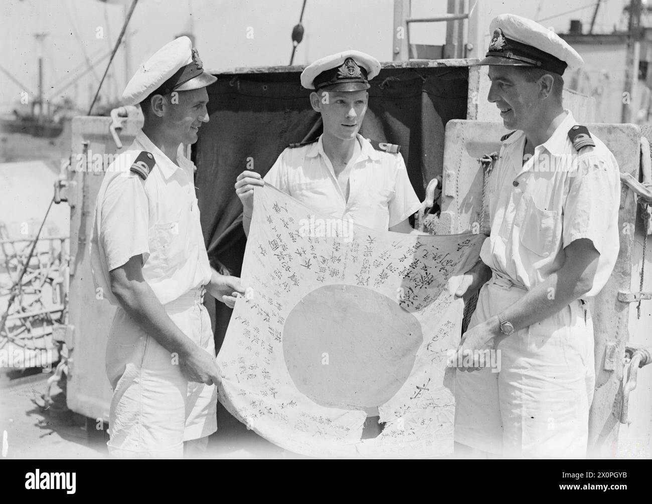 Una fotografia del 3 marzo 1945 mostra la HMS Pathfinder che sventola una bandiera giapponese catturata, un dono dei Royal Garwhal Rifles in seguito al supporto durante l'azione sull'isola Ramree, con gli ufficiali della nave ritratti accanto alla bandiera. Foto Stock