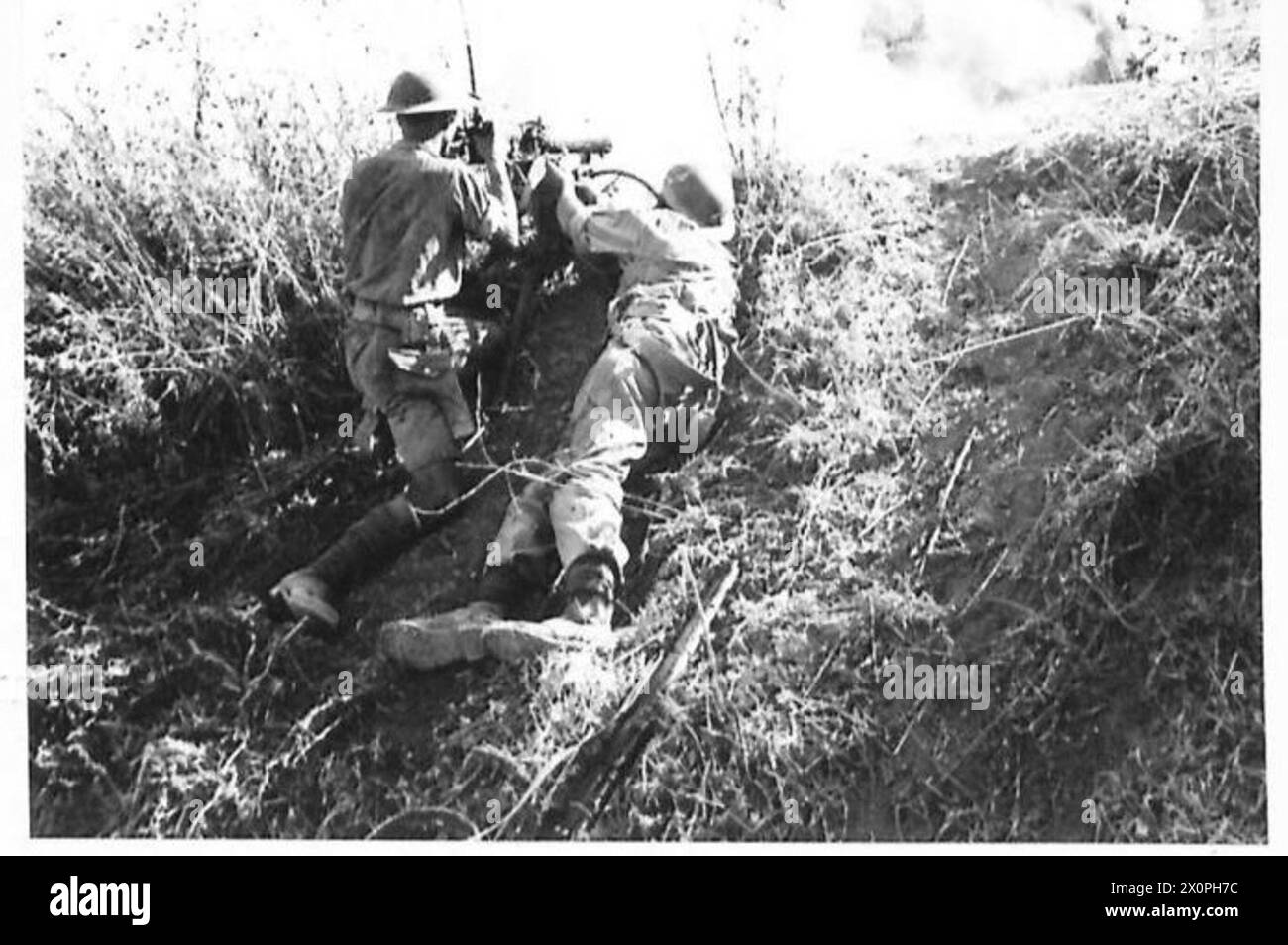 I soldati Crowhurst e Dickson del Middlesex Regiment spostano la loro pistola in una nuova posizione durante l'invasione della Sicilia, con una bomba che esplode nelle vicinanze. Foto Stock