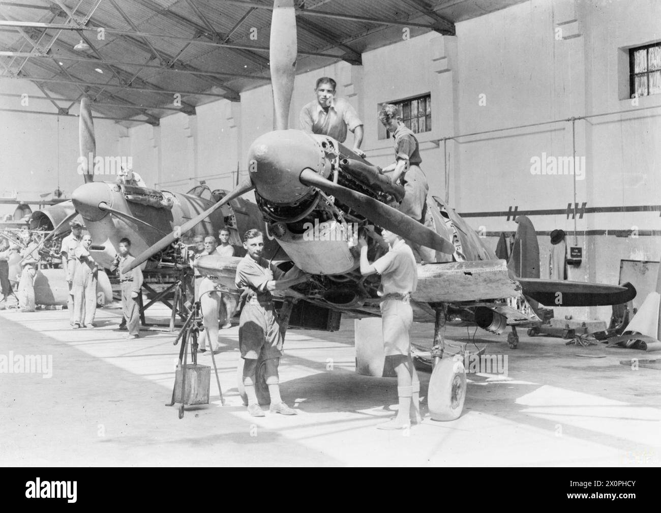 ROYAL AIR FORCE: OPERAZIONI A MALTA, GIBILTERRA E NEL MEDITERRANEO, 1940-1945. - Installatori RAF e operai civili maltesi che riparano i Supermarine Spitfire Mark vs danneggiati in un capannone di manutenzione a Ta Kali Foto Stock