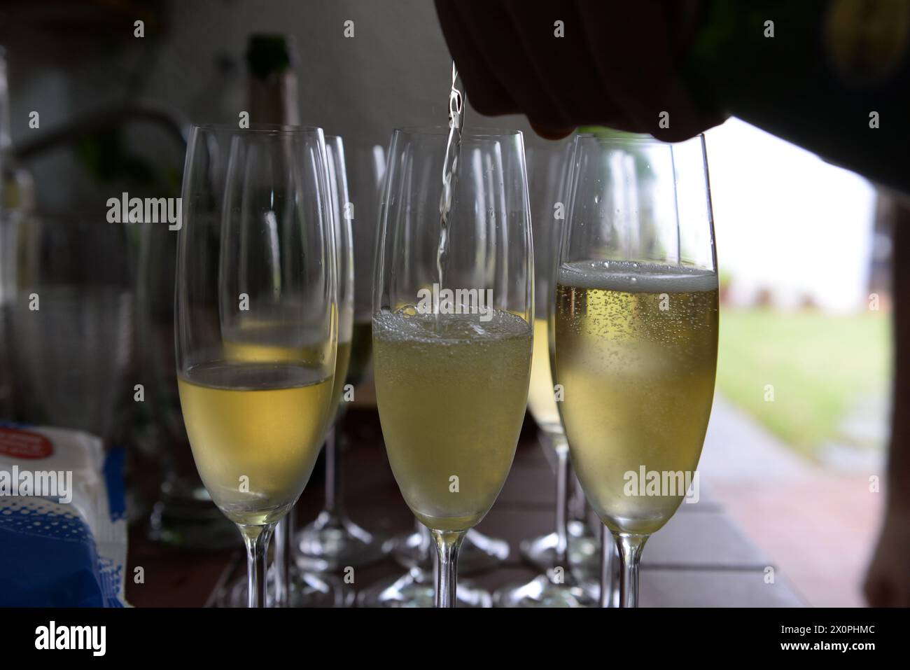 Una vista ravvicinata di diversi flauti di champagne frizzanti, alcuni riempiti di liquido effervescente, disposti su un tavolo, forse in occasione di un evento come un matrimonio Foto Stock