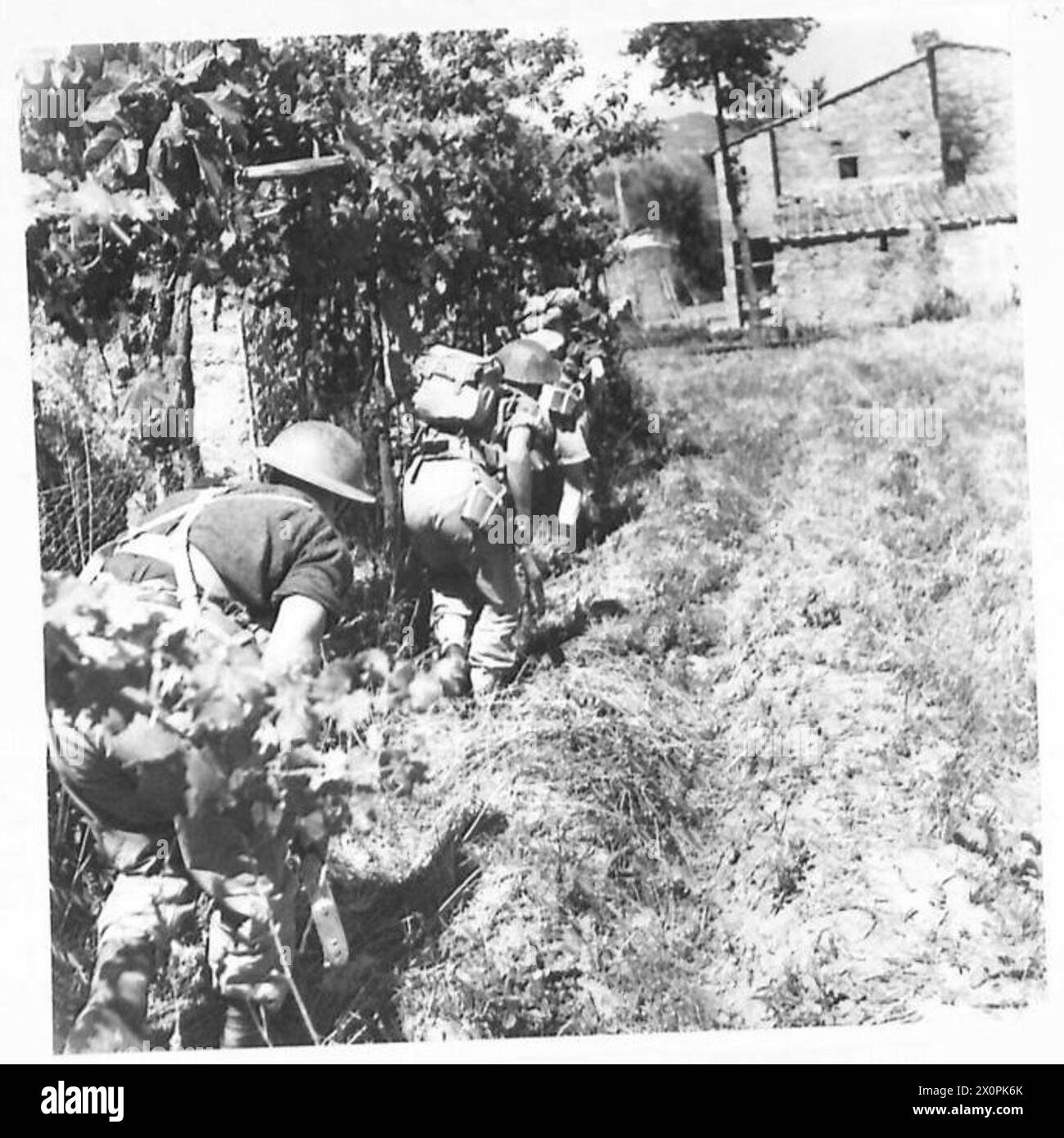 Negativo fotografico che mostra i soldati neozelandesi dell'Ottava Armata che usano la copertura mentre si avvicinano a un sospetto avamposto nemico. Foto Stock