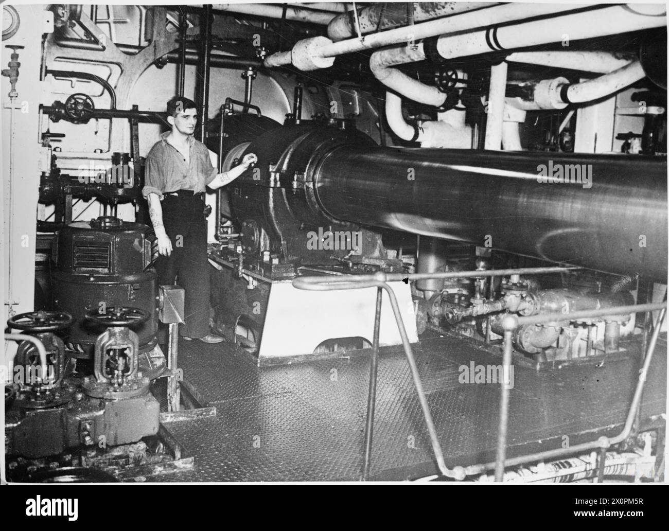 Un membro dell'equipaggio sta accanto all'albero di trasmissione principale sulla HMS Tracker, una portaerei di scorta, mentre la nave naviga nel Nord Atlantico nel 1942. Negativo fotografico. Foto Stock
