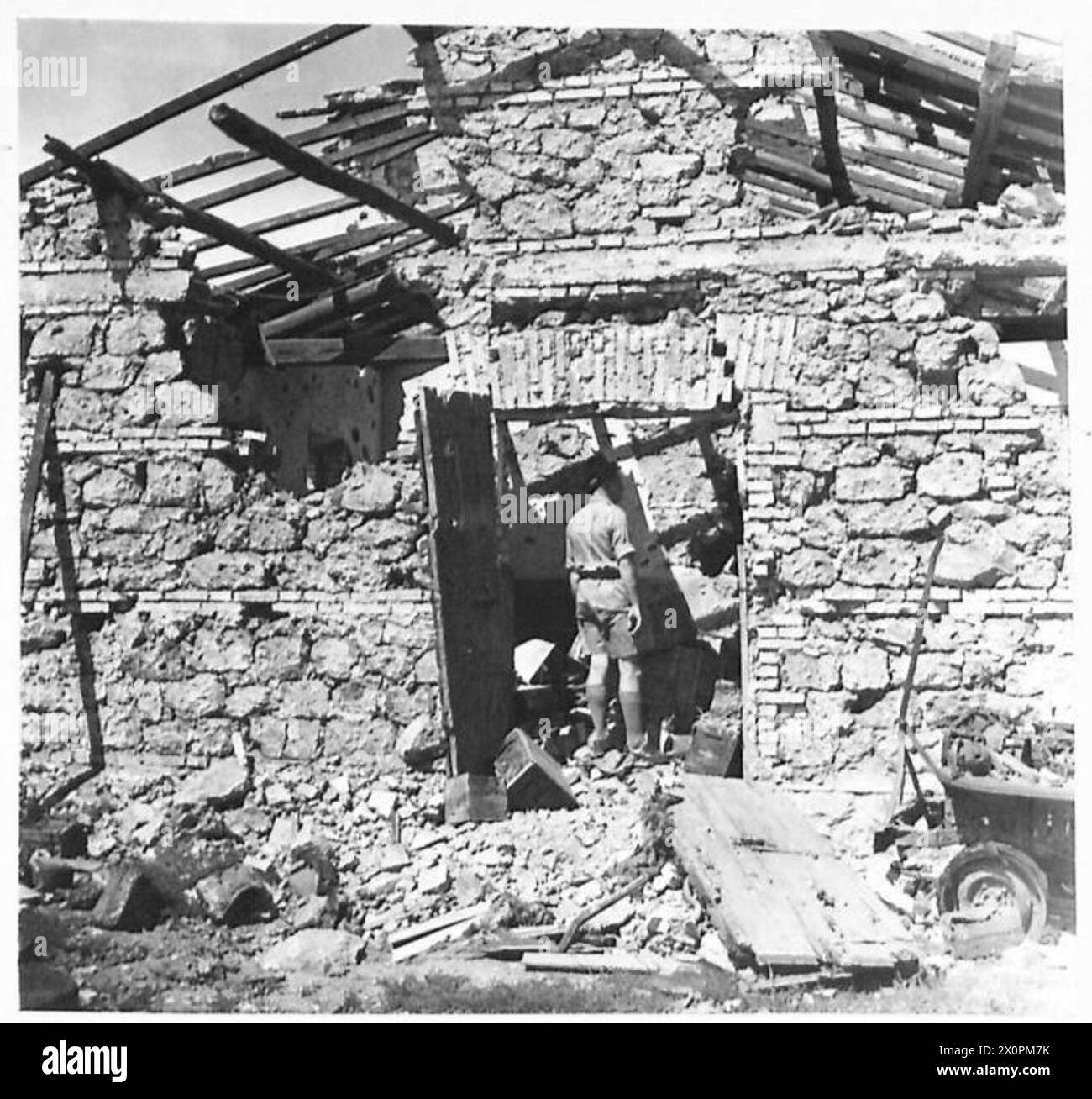 Un ufficiale si trova all'interno di un edificio che in precedenza serviva come quartier generale del suo Battaglione ad Anzio, documentato in un negativo fotografico dell'esercito britannico. Foto Stock