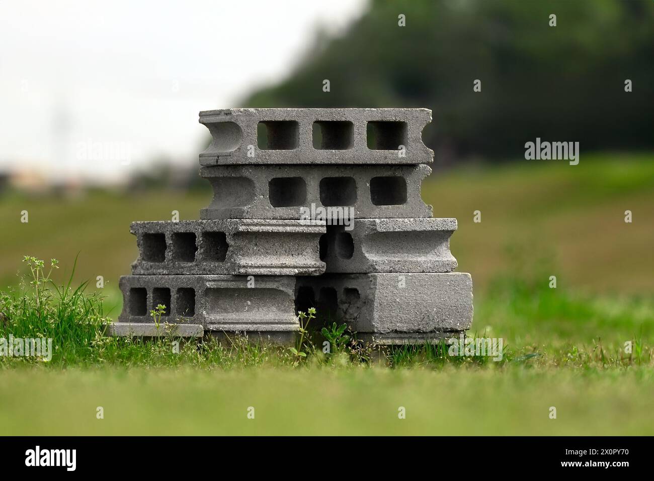 Un mucchio di blocchi cavi di calcestruzzo impilati uno sopra l'altro nell'erba. Foto Stock