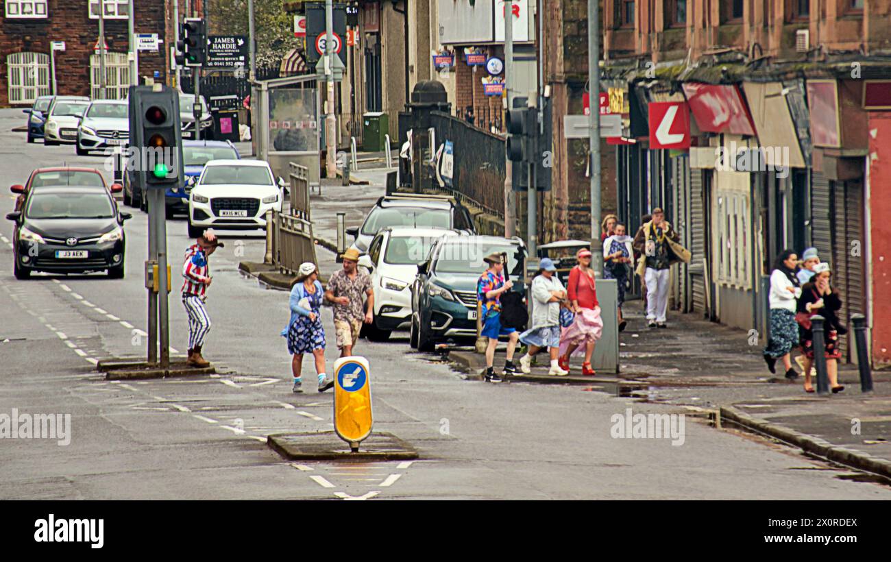 Glasgow, Scozia, Regno Unito. 13 aprile 2024: Regno Unito Meteo: Festaioli vestiti degli anni '70 che attraversano la strada Wet and Windy in città mentre la gente lottava nella capitale dello shopping e nello stile di Mile of Scotland, Buchanan Street. Credit Gerard Ferry/Alamy Live News Foto Stock