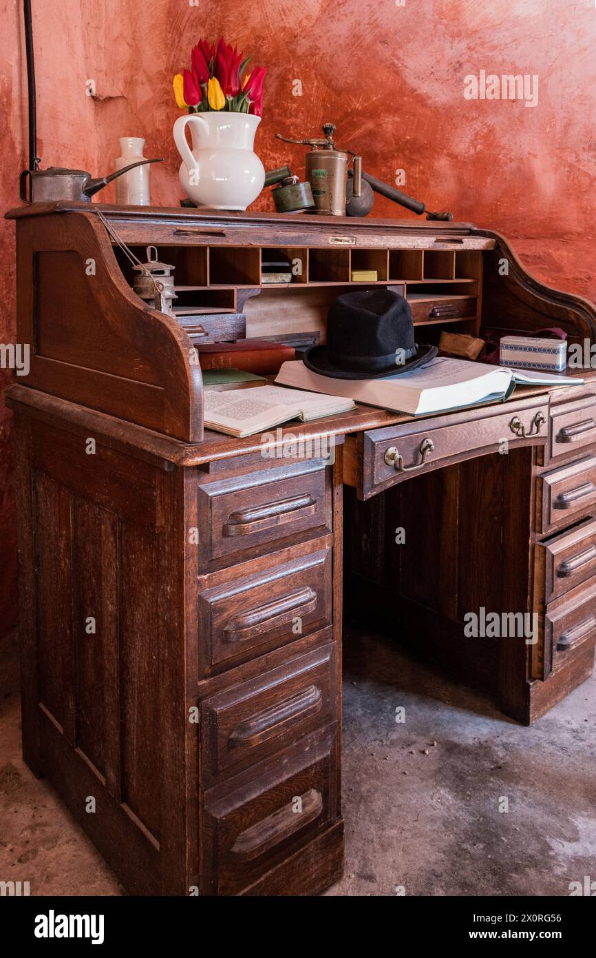 Un'antica lampada da uragano, un cappello da bowler, un vaso bianco, una latta per tabacco francese, libri aperti e spruzzatori in ottone su un ufficio in legno vecchio stile. Stile retrò. Foto Stock