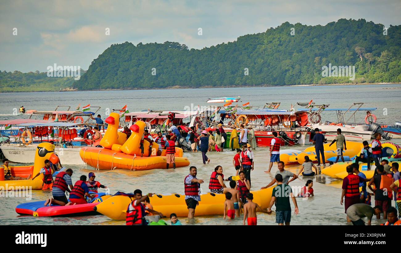 C'è un grande gruppo di individui che partecipano alle attività in spiaggia, anche se le loro identità e le loro emozioni specifiche non sono distinguibili. Foto Stock