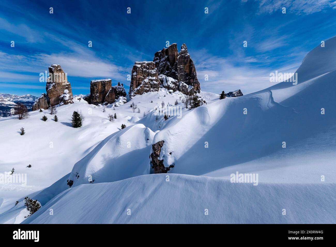 Snowdrift creazione di strutture artistiche in inverno, pendii innevati del paesaggio alpino dolomitico e cime del gruppo delle cinque Torri in lontananza Foto Stock