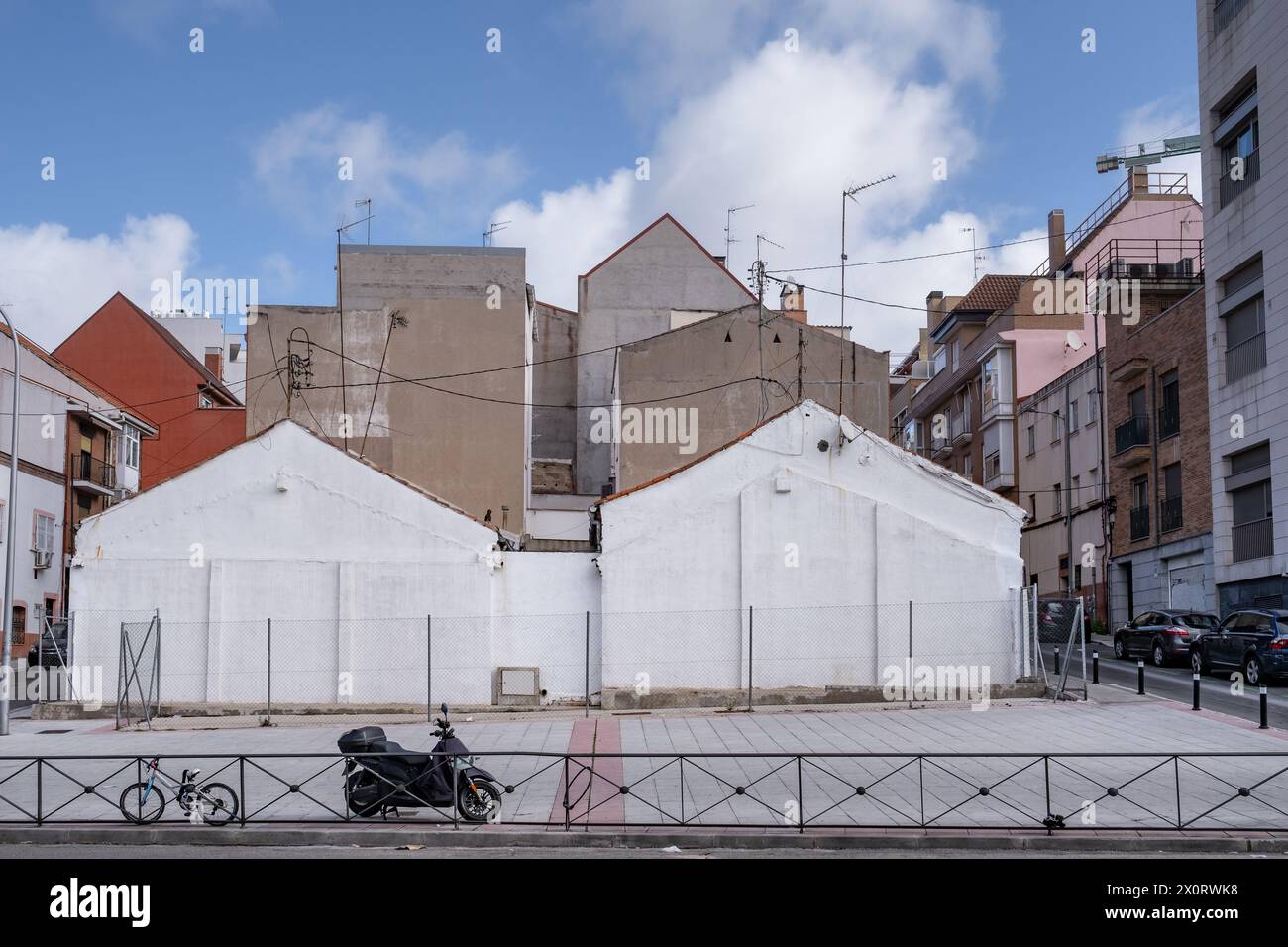 Scena urbana con un terreno non sviluppato dove i resti di una vecchia dimora con pareti di colore chiaro possono essere visti sotto un cielo soleggiato e limpido. Foto Stock
