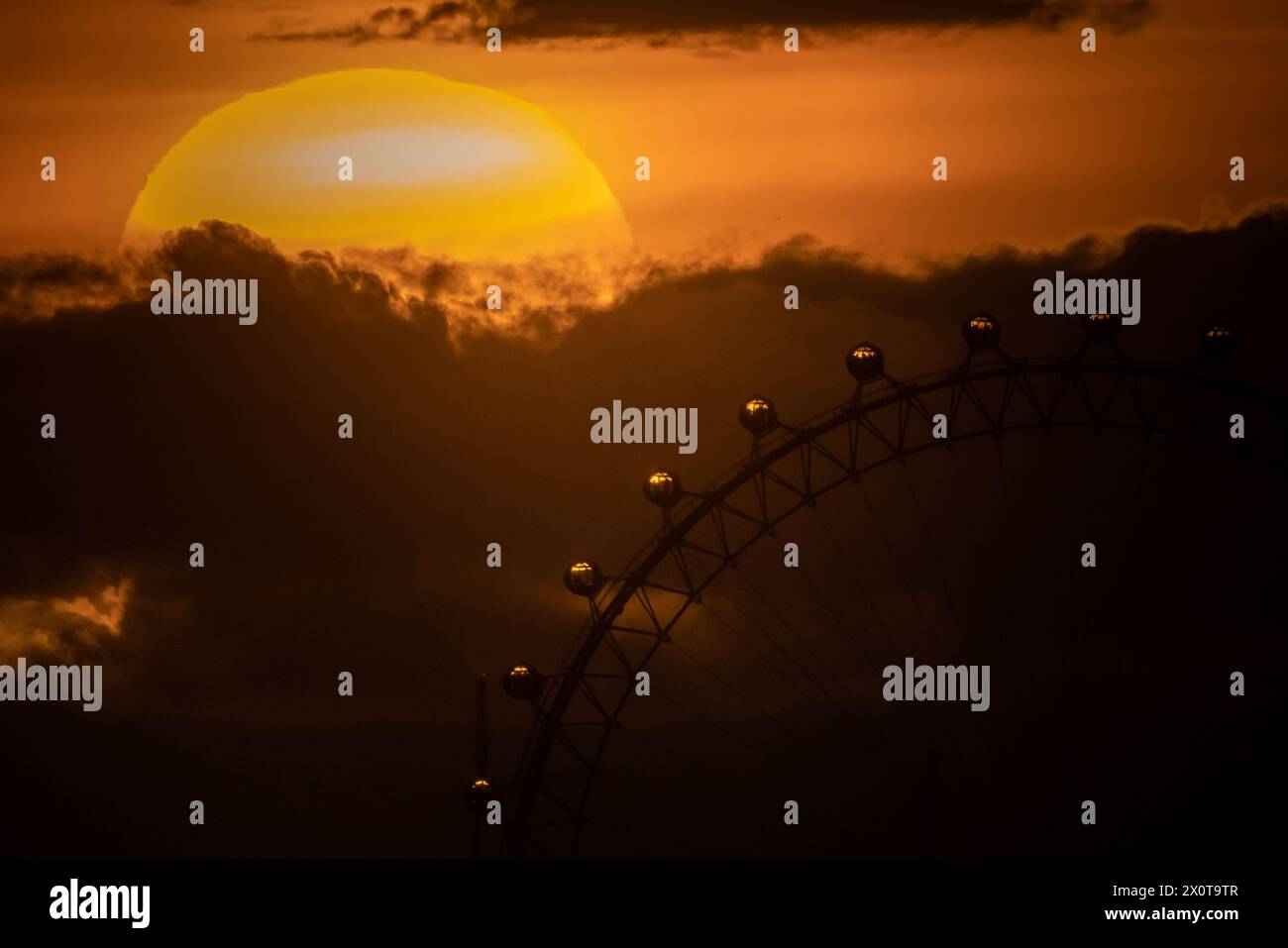 Londra, Regno Unito. 13 aprile 2024. Meteo nel Regno Unito: Tramonto spettacolare vicino alla ruota panoramica di London Eye che termina un sabato caldo che il Met Office conferma come il giorno più caldo dell'anno fino a quando le temperature si innalzano al di sopra della media. Le temperature superavano i 21C in almeno due luoghi - St James Park, nel centro di Londra, e Northolt, nella zona ovest di Londra - quando un pennacchio d'aria dell'Atlantico si spostava da sud-ovest. Crediti: Guy Corbishley/Alamy Live News Foto Stock